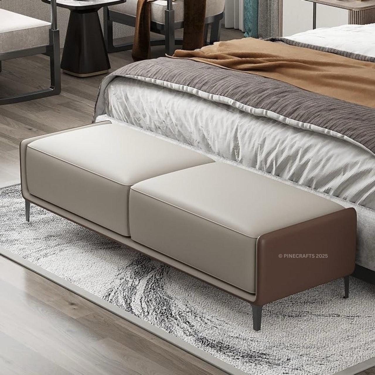 Beige bench in front of a bed with a brown blanket on a wooden floor.