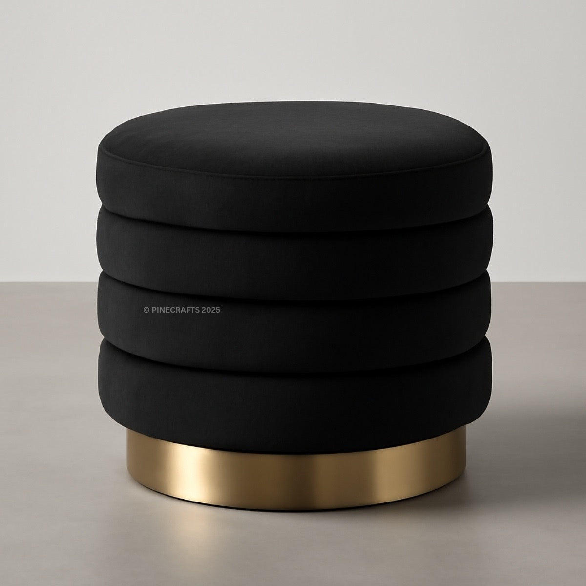 Black ottoman with a gold base on a neutral background