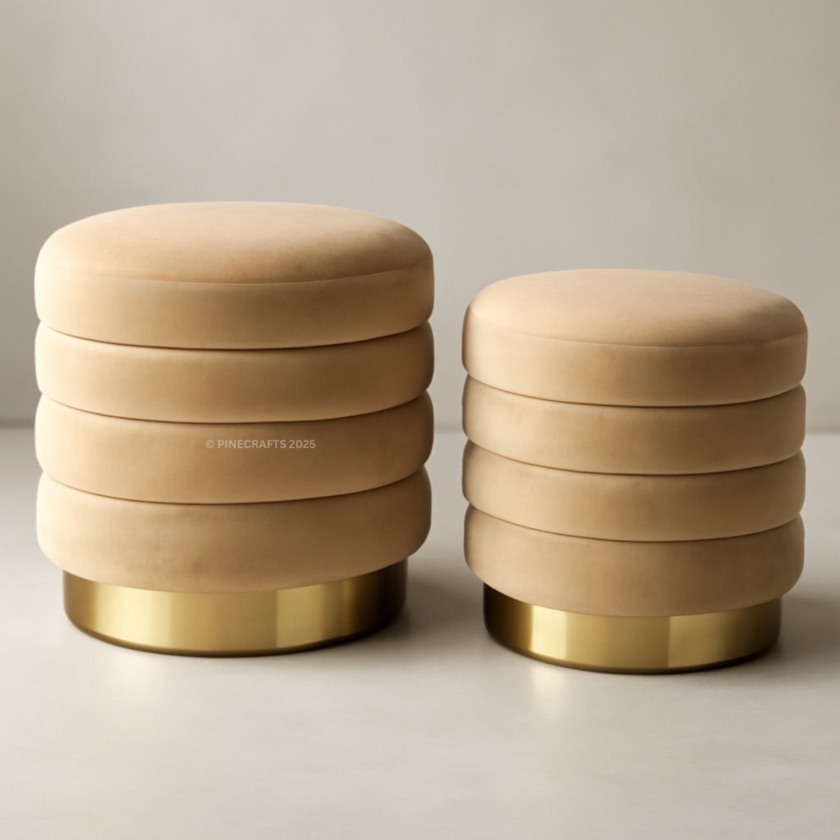 Two beige stools with gold bases on a light background