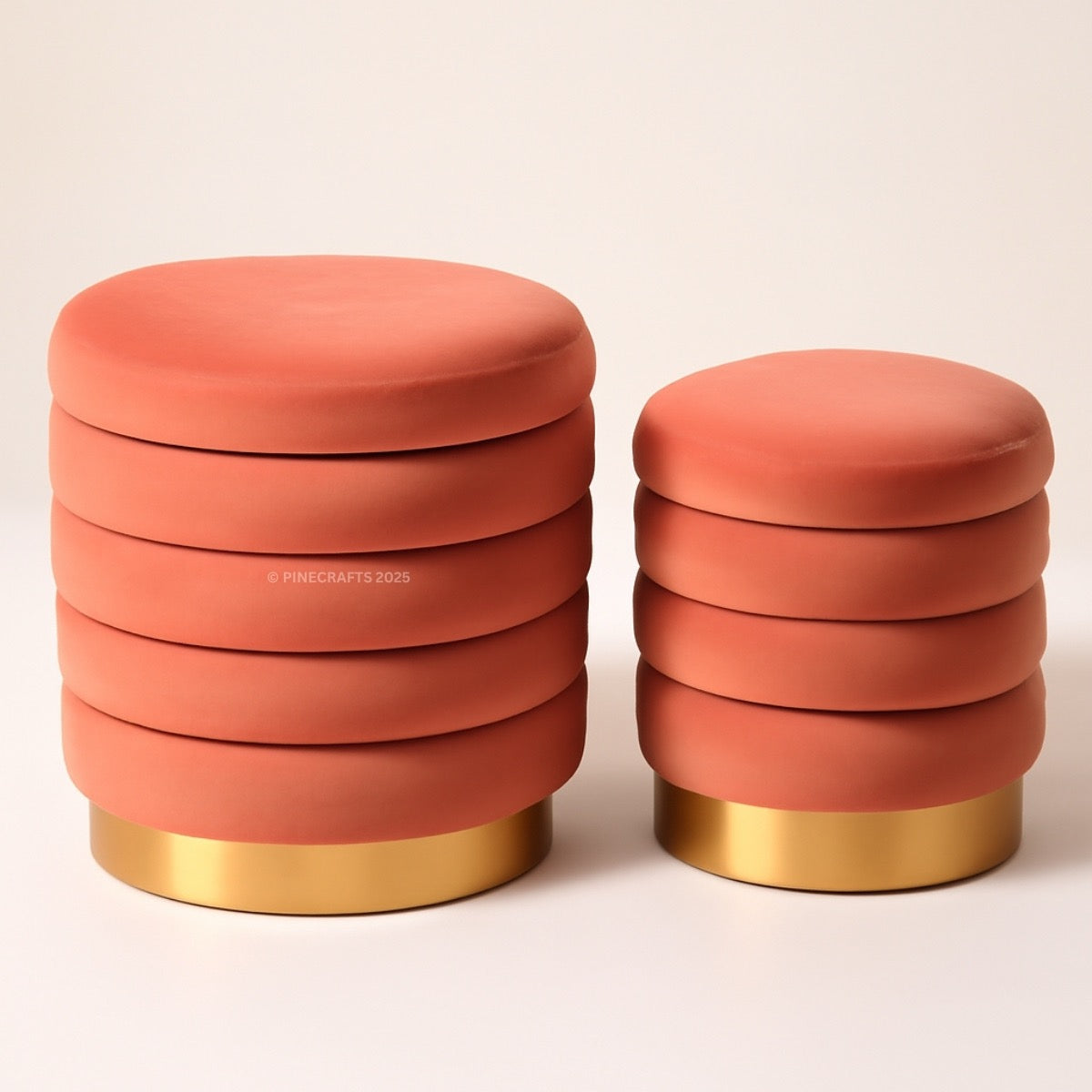 Two coral-colored stools with gold bases on a beige background