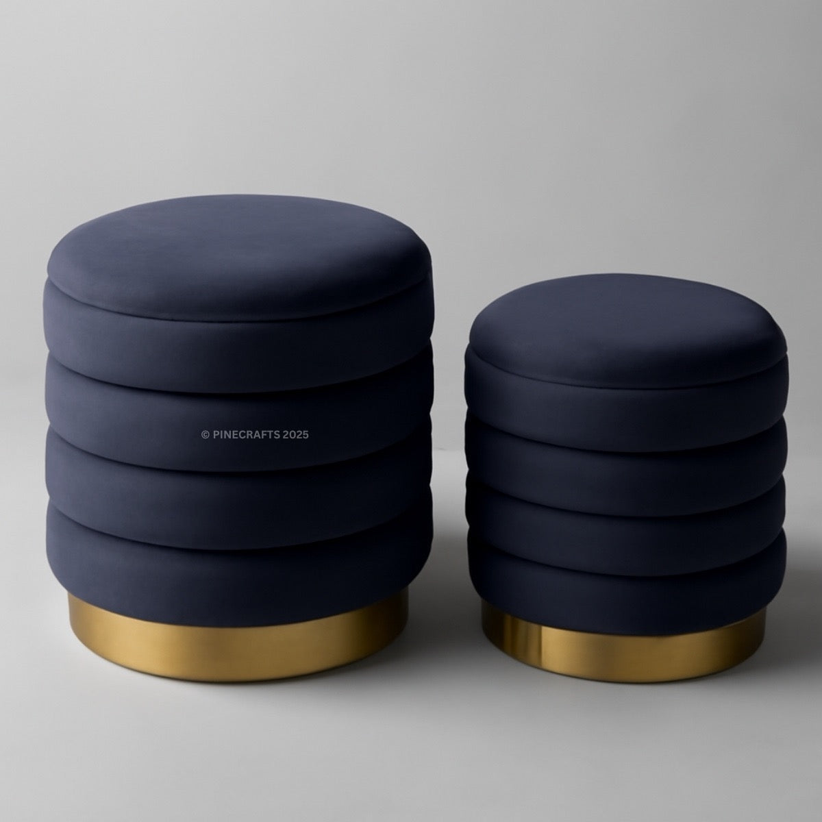 Two navy blue stools with gold bases on a gray background