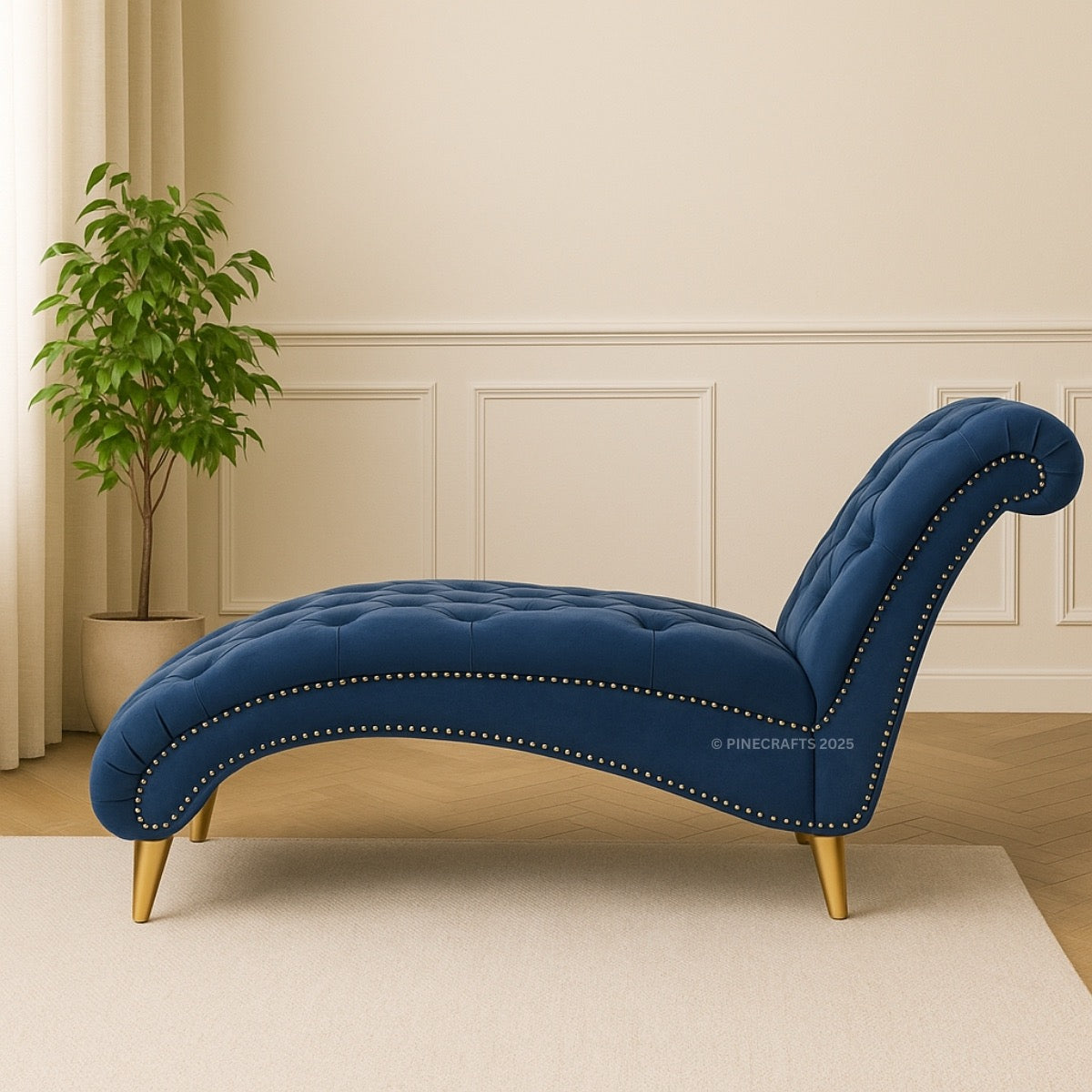 Blue tufted chaise lounge with gold legs in a room with a plant and panelled wall.