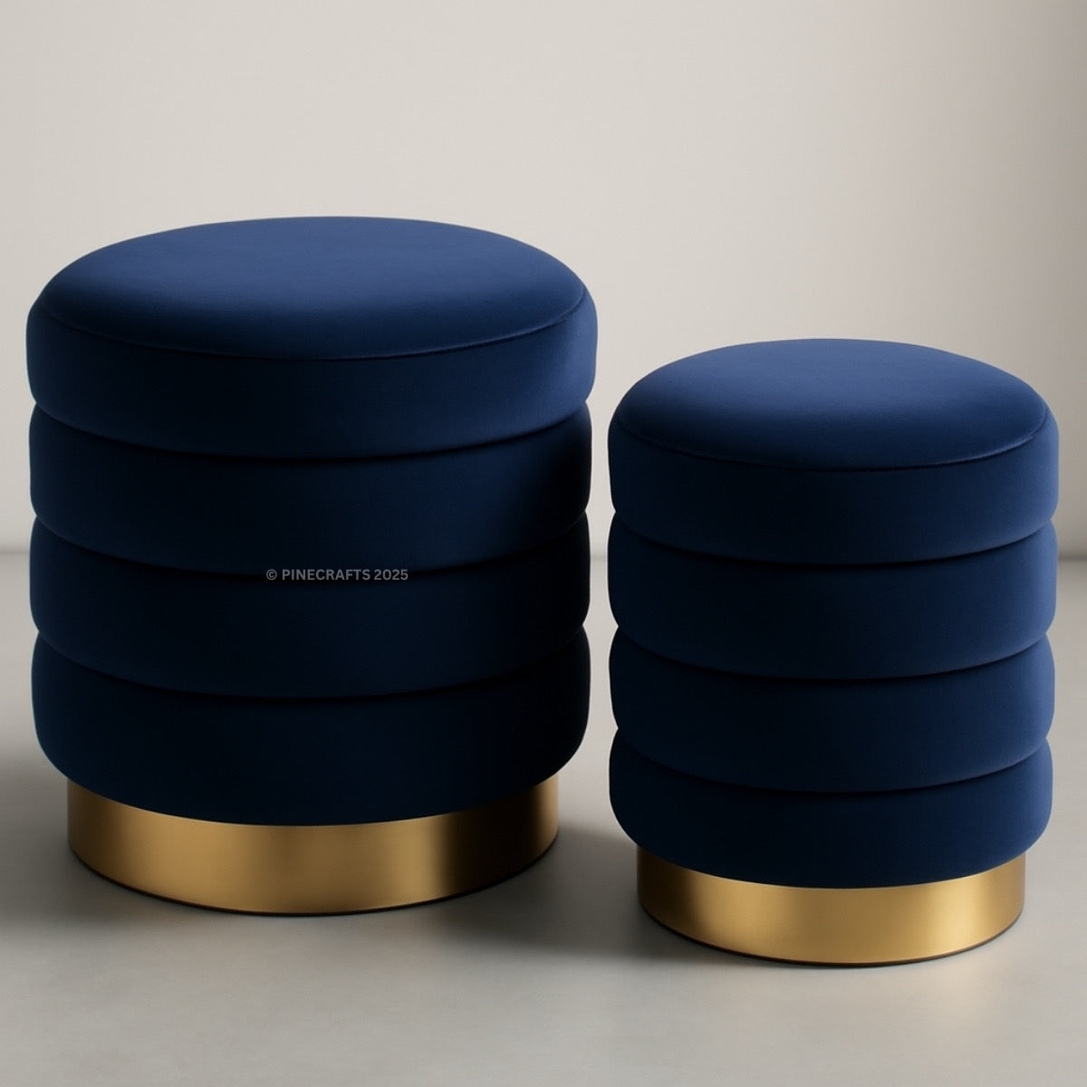 Two navy blue ottomans with gold bases on a neutral background