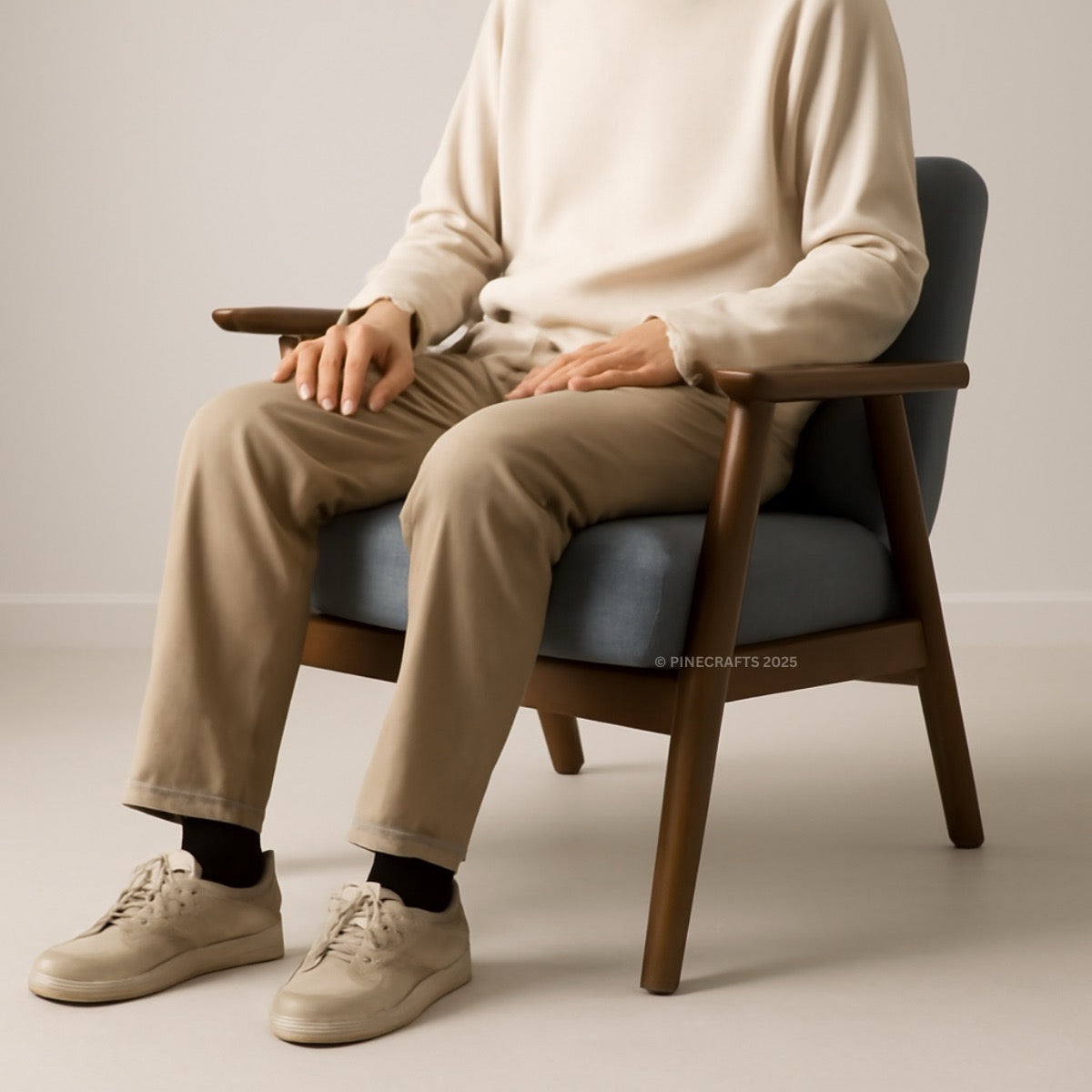 Person sitting on a wooden chair wearing a beige sweater, pants, and shoes.