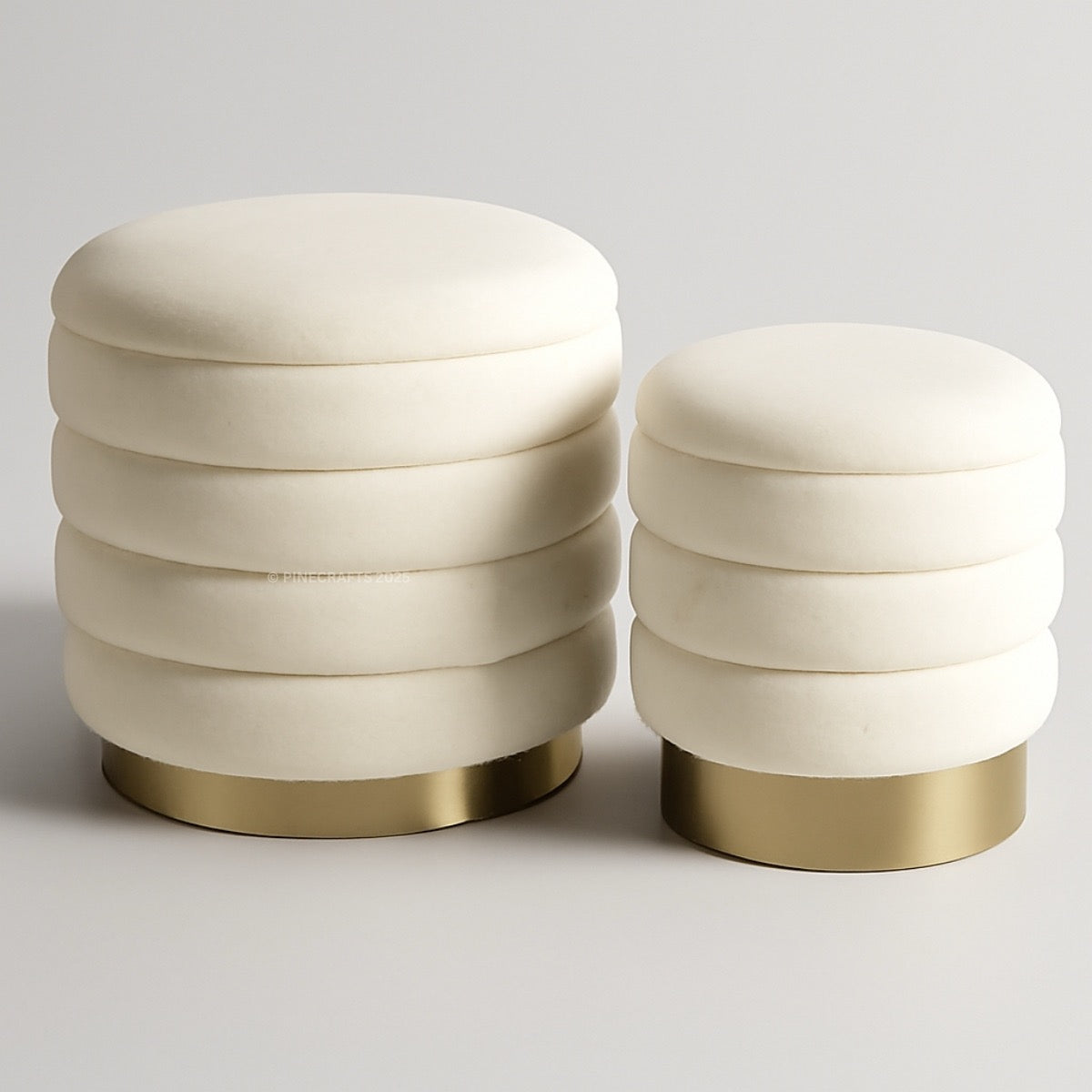 Two cream-colored stools with gold bases on a light gray background
