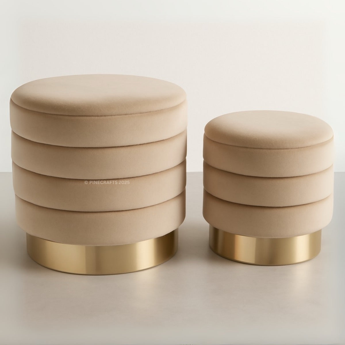 Two beige stools with gold bases on a light background
