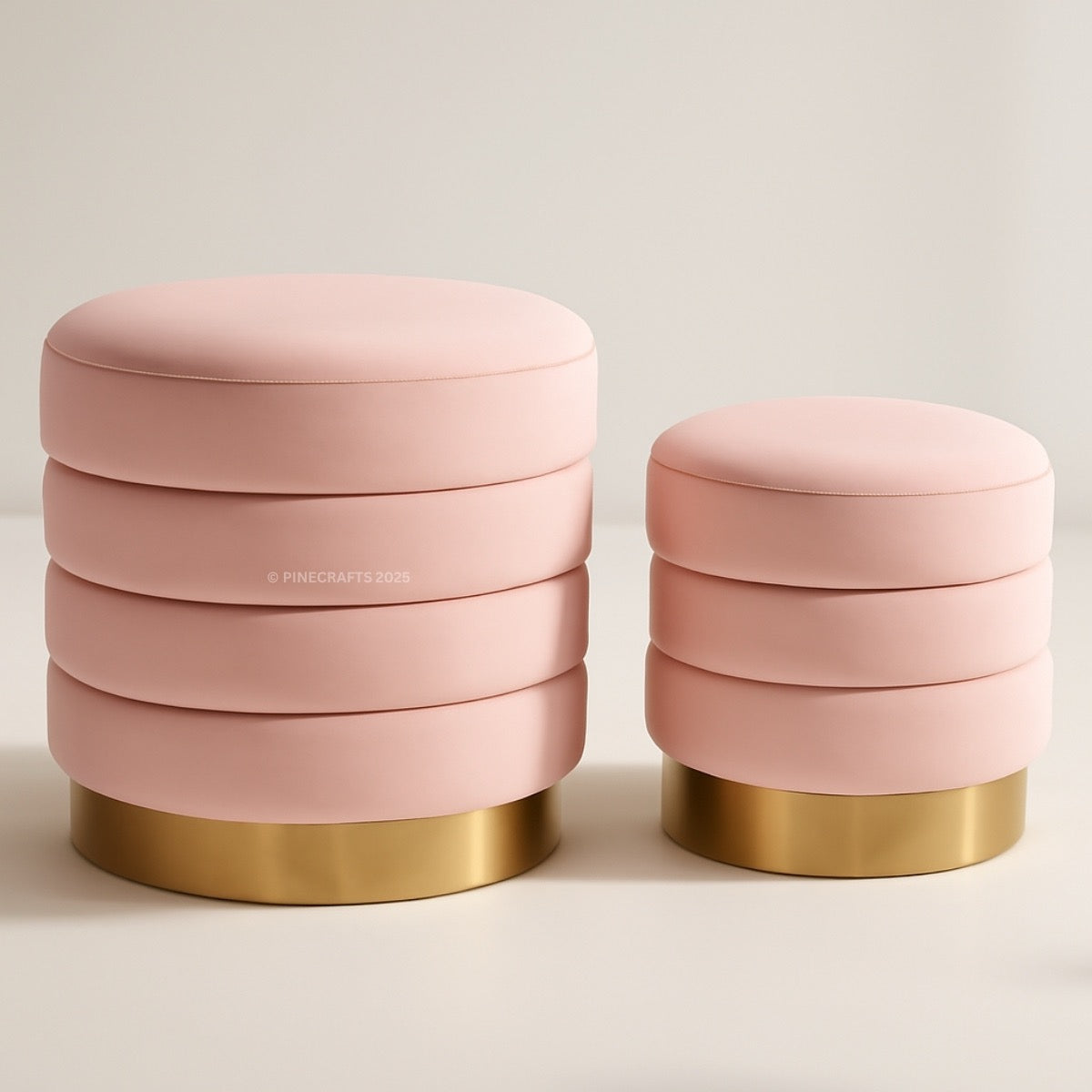 Two pink ottomans with gold bases on a light background