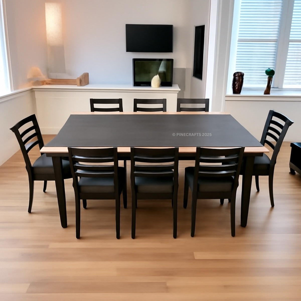 Dining room with a long black table and eight chairs in a well-lit room.
