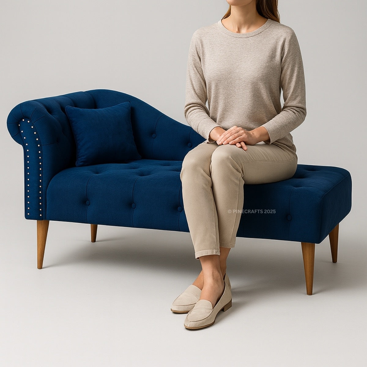 Person sitting on a blue tufted bench with a neutral background