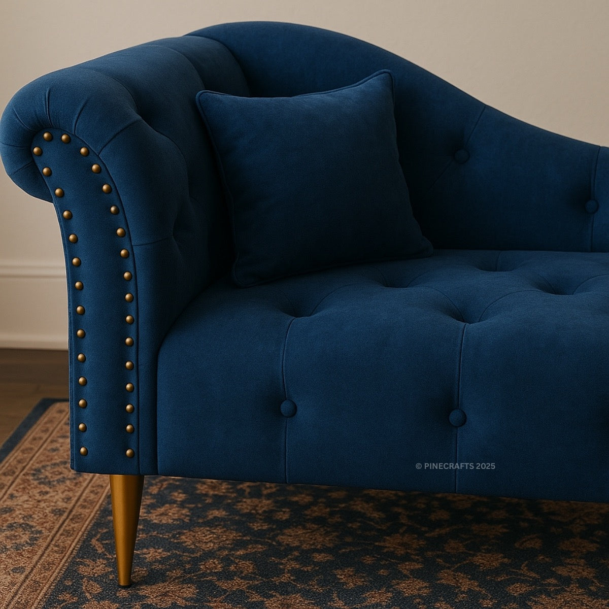 Blue velvet sofa with tufted backrest and nailhead trim on a patterned rug.