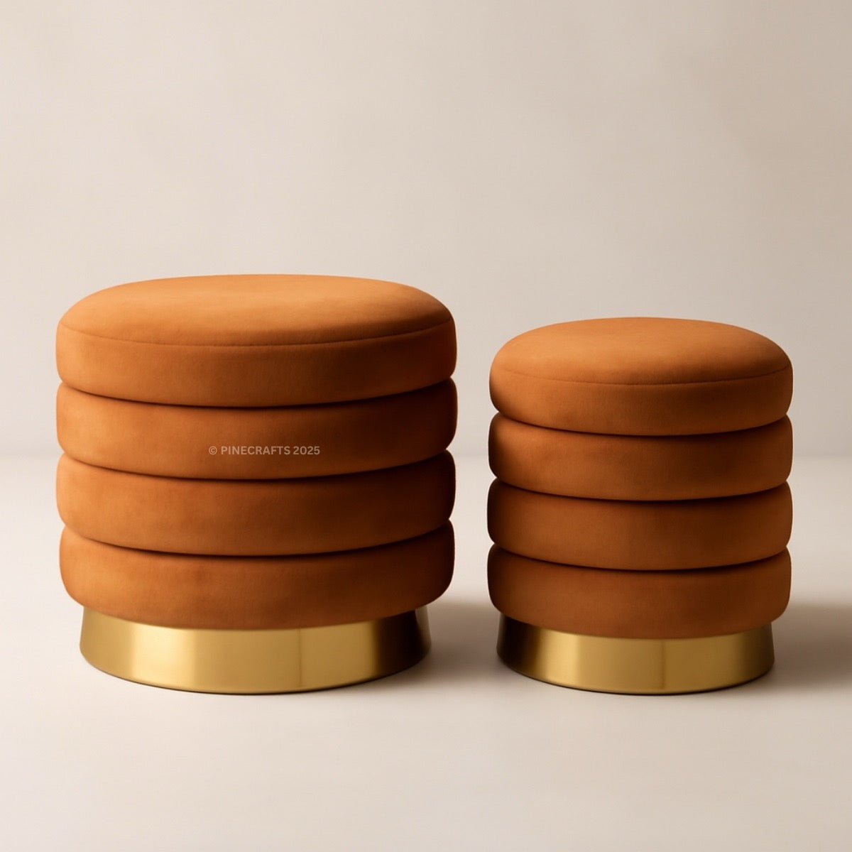 Two orange stools with gold bases on a beige background
