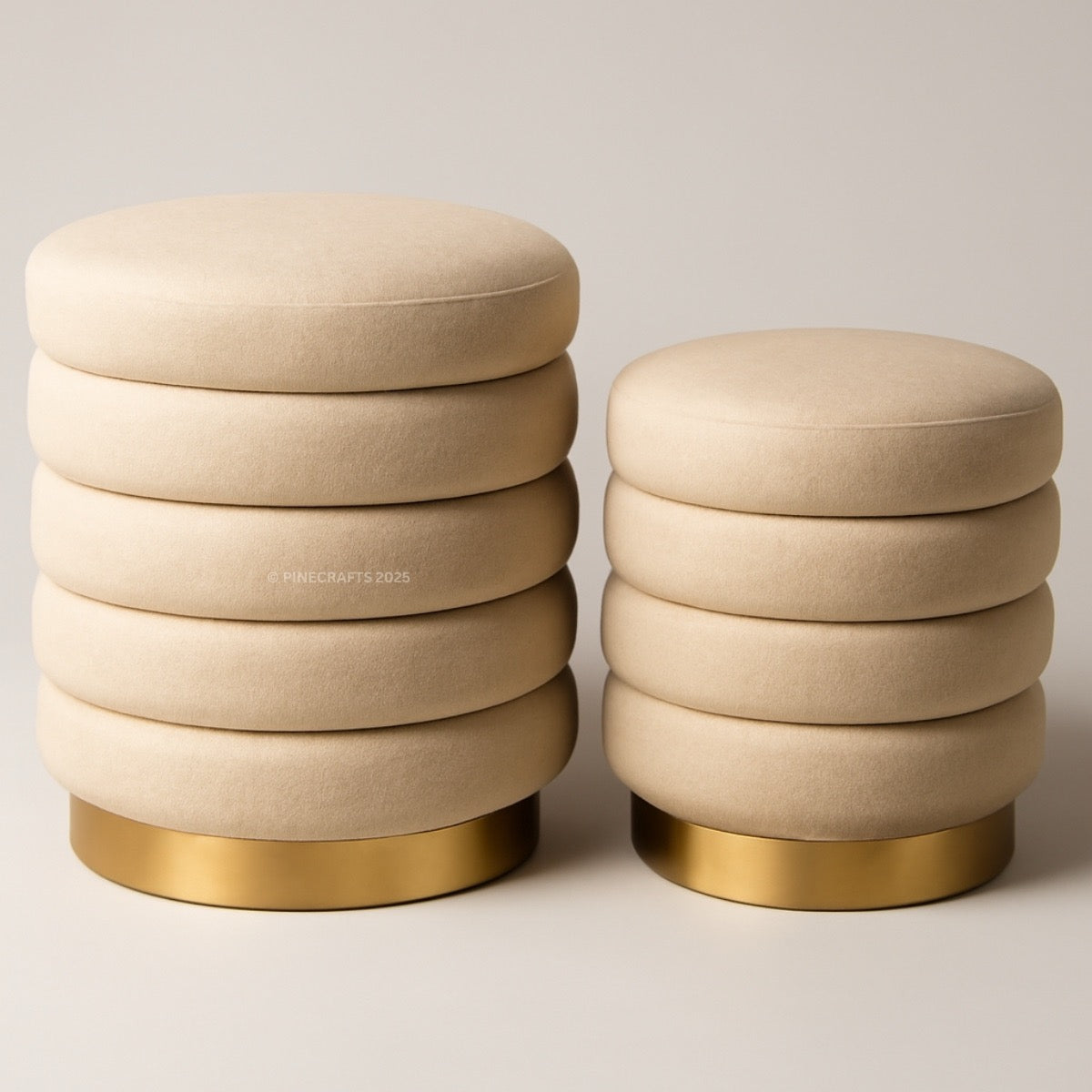Two beige ottomans with gold bases on a light background