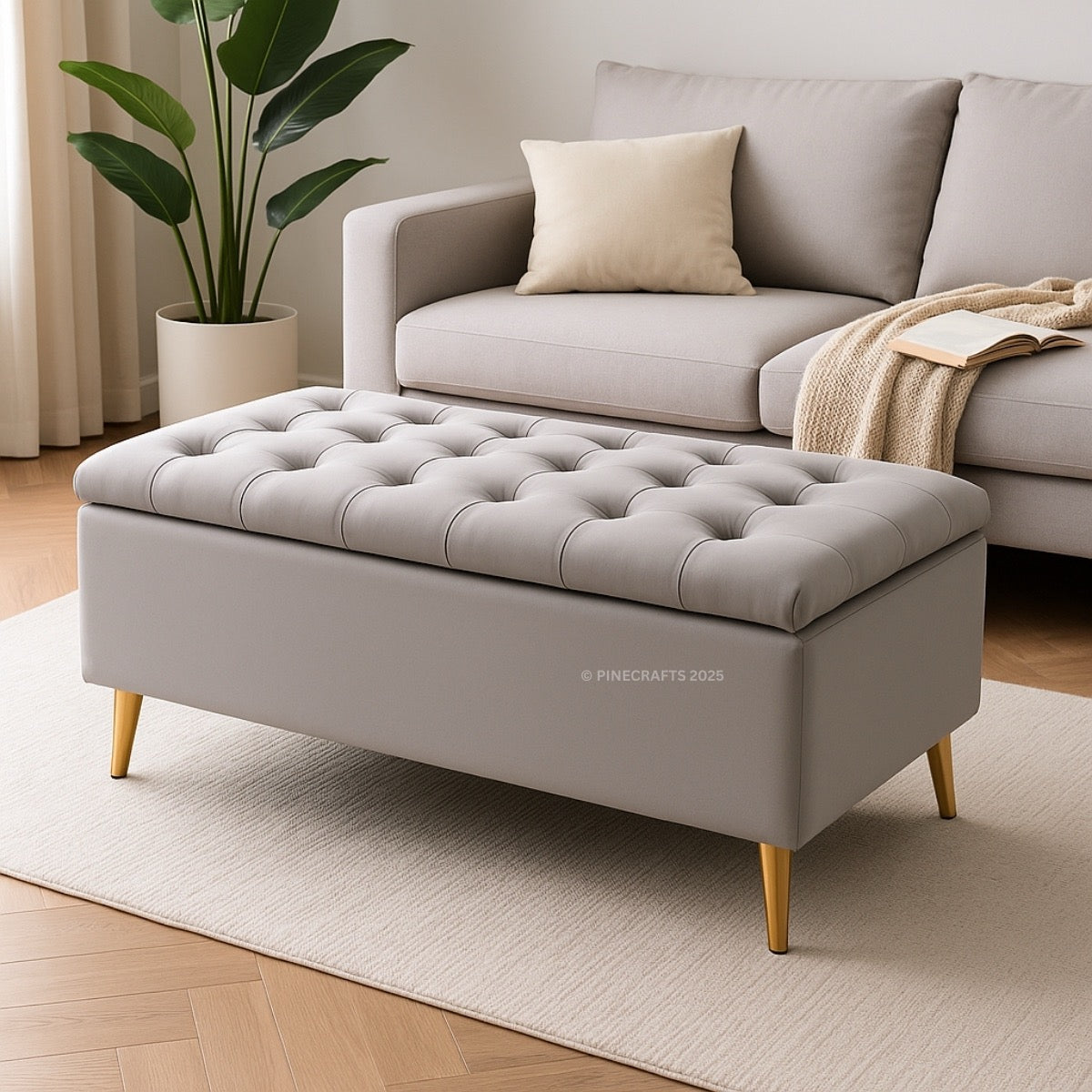 Gray tufted ottoman in a living room setting with a couch and plant.