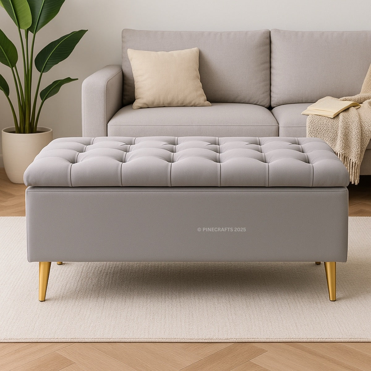 Gray tufted ottoman with gold legs in a living room setting.