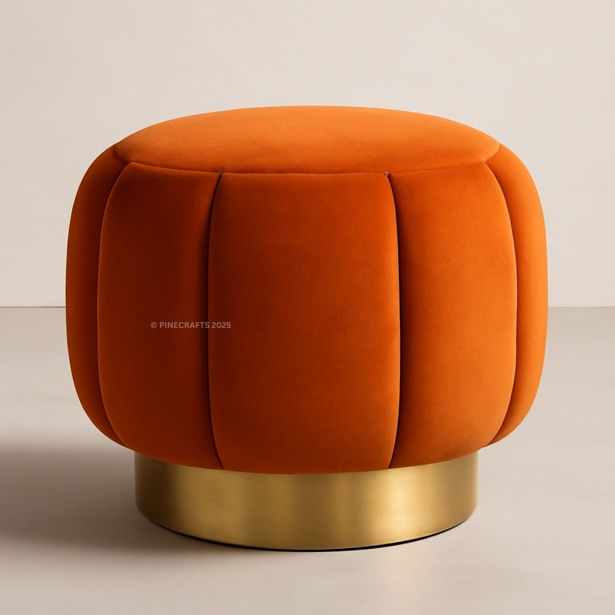 Orange velvet ottoman with a gold base on a beige background