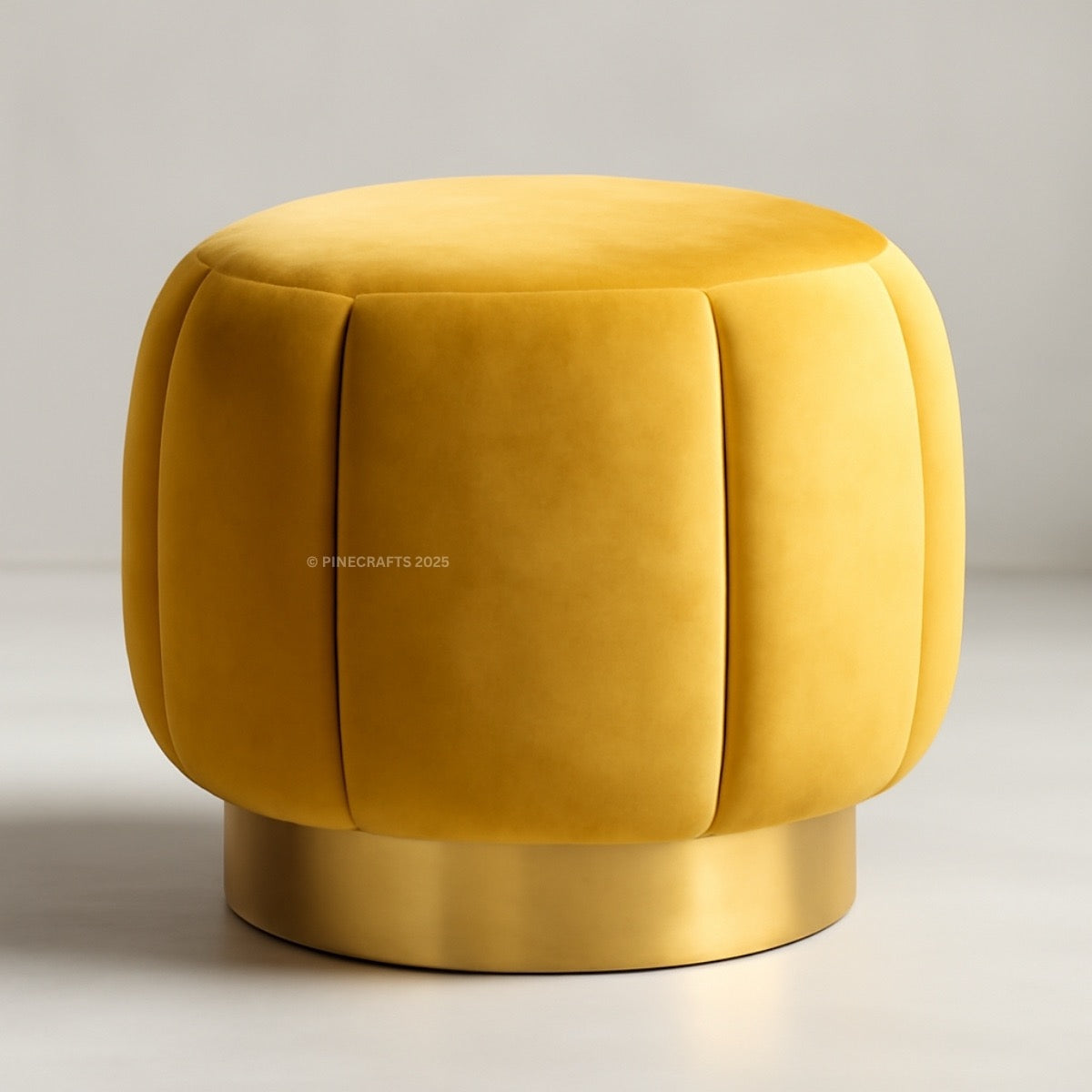 Yellow velvet ottoman with a metallic base on a neutral background