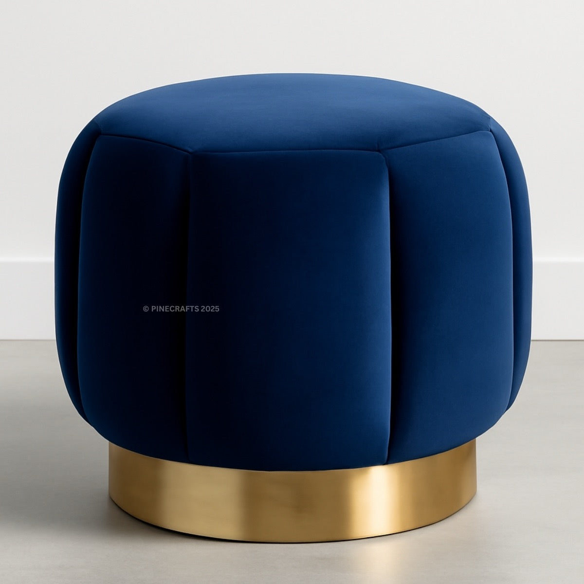 Blue velvet ottoman with a gold base on a light gray background