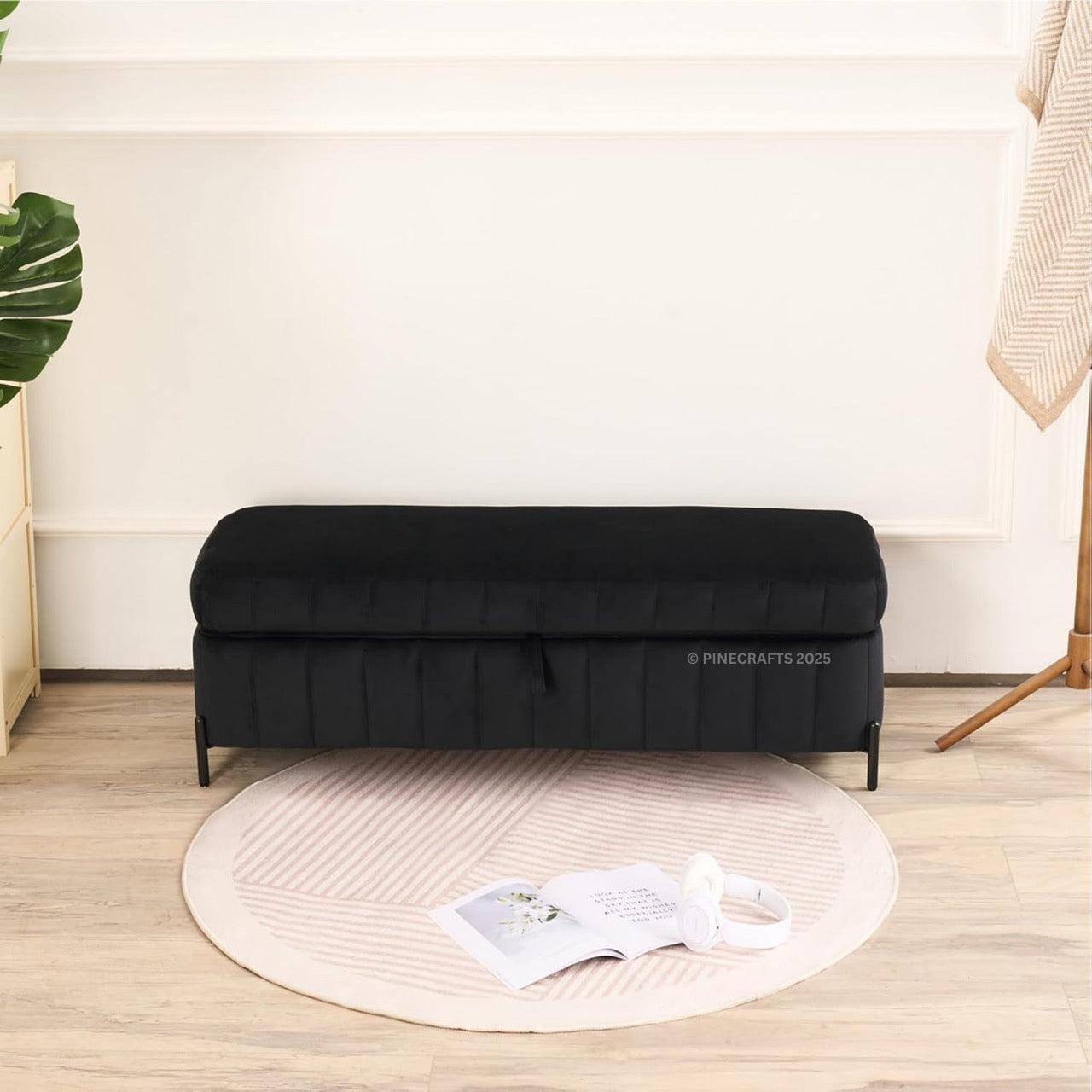 Black sofa bed in a room with a round rug and plant