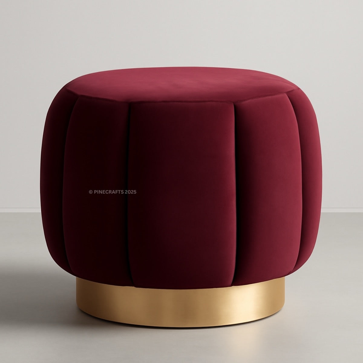 Maroon ottoman with a gold base on a light gray background
