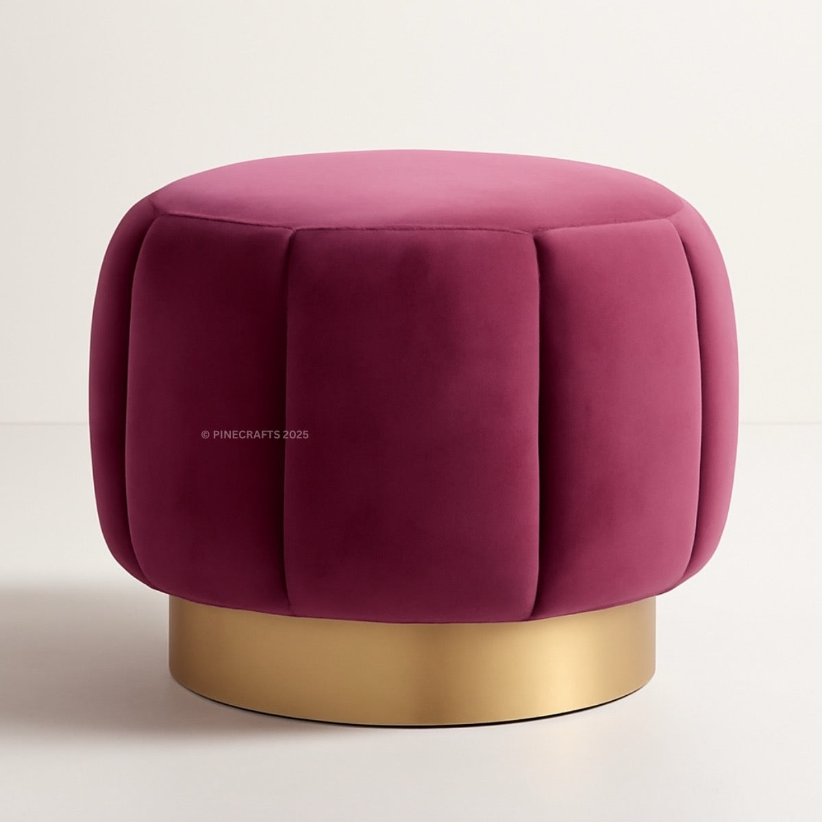 Pink velvet ottoman with a gold base on a light beige background