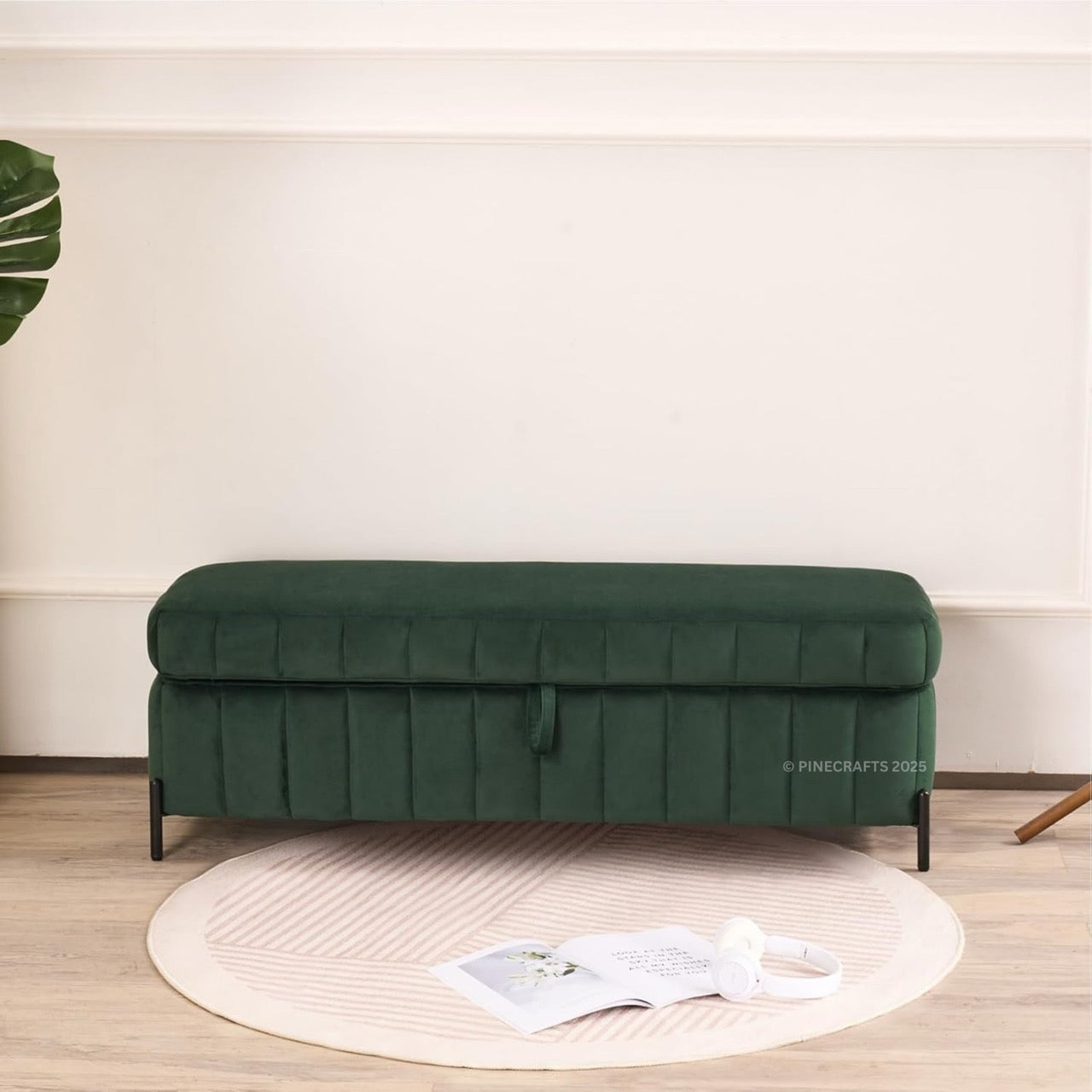 Green bench in a room with a light-colored wall and wooden floor.