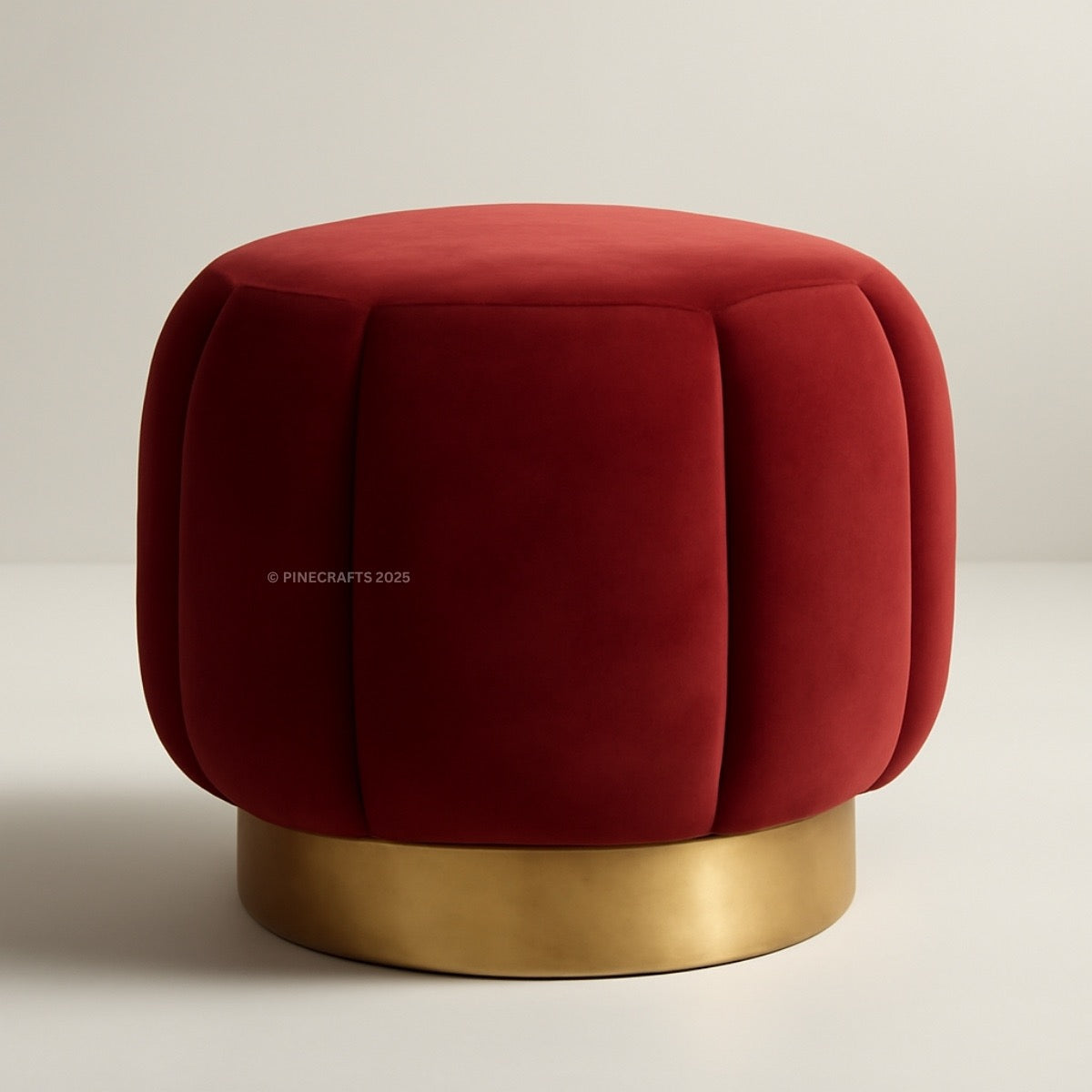 Red velvet ottoman with a gold base on a beige background