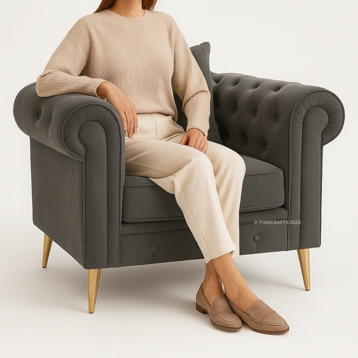 Person sitting on a gray armchair wearing a beige sweater and pants with brown shoes.