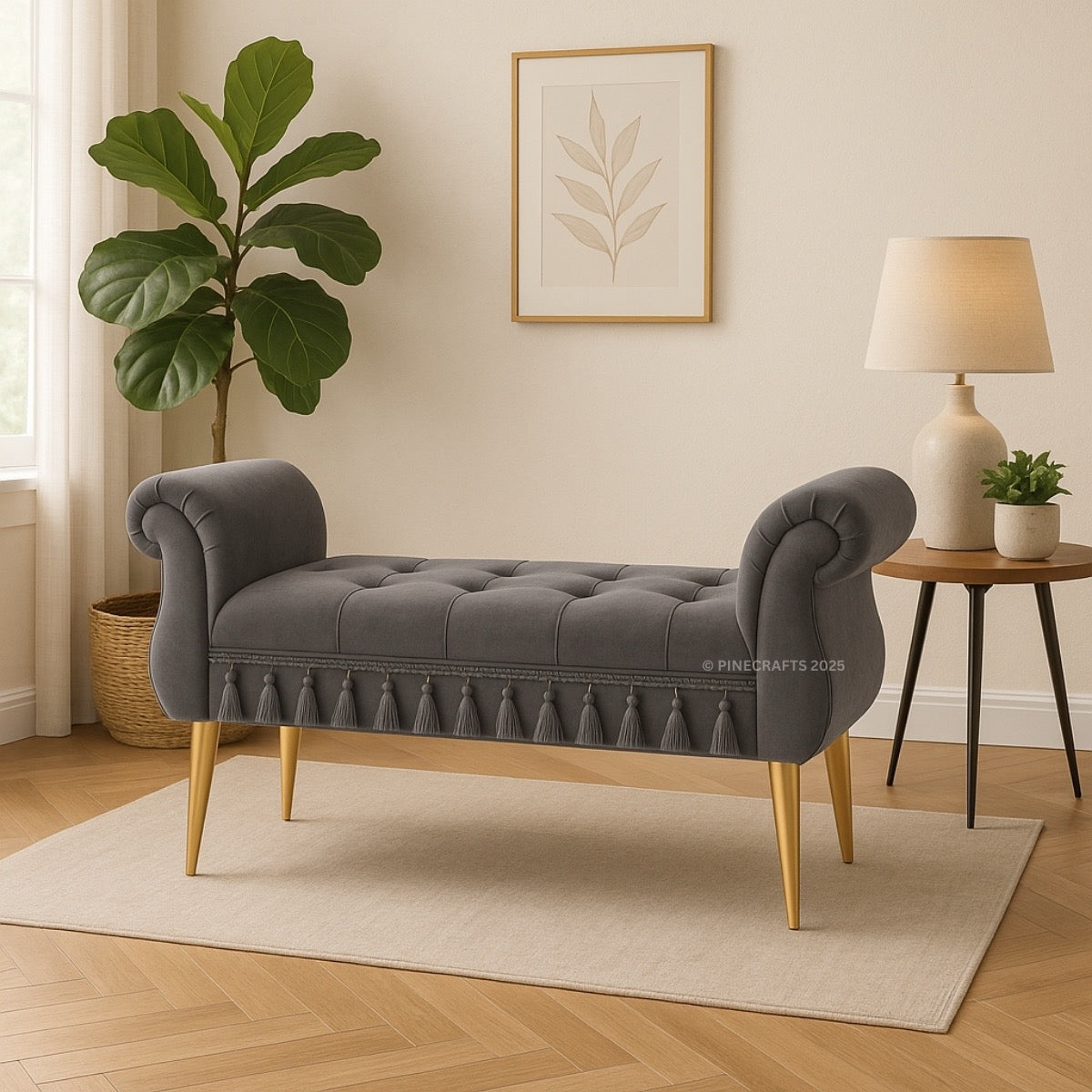Gray tufted bench with gold legs in a room with a plant, lamp, and framed picture on the wall.