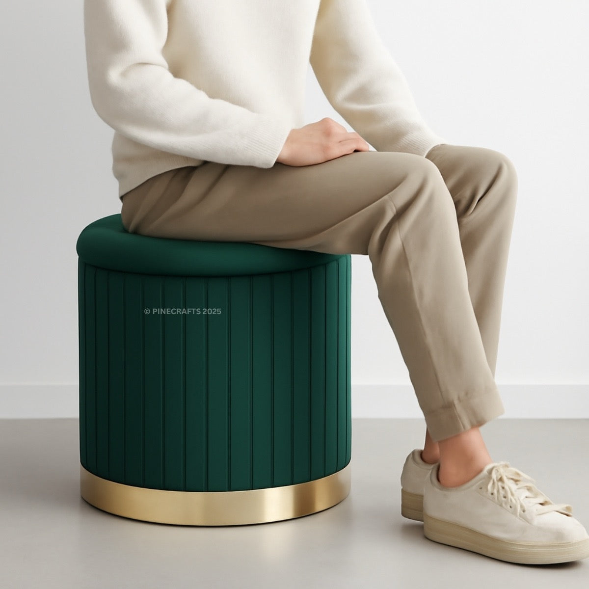 Person sitting on a green stool with a gold base against a white background