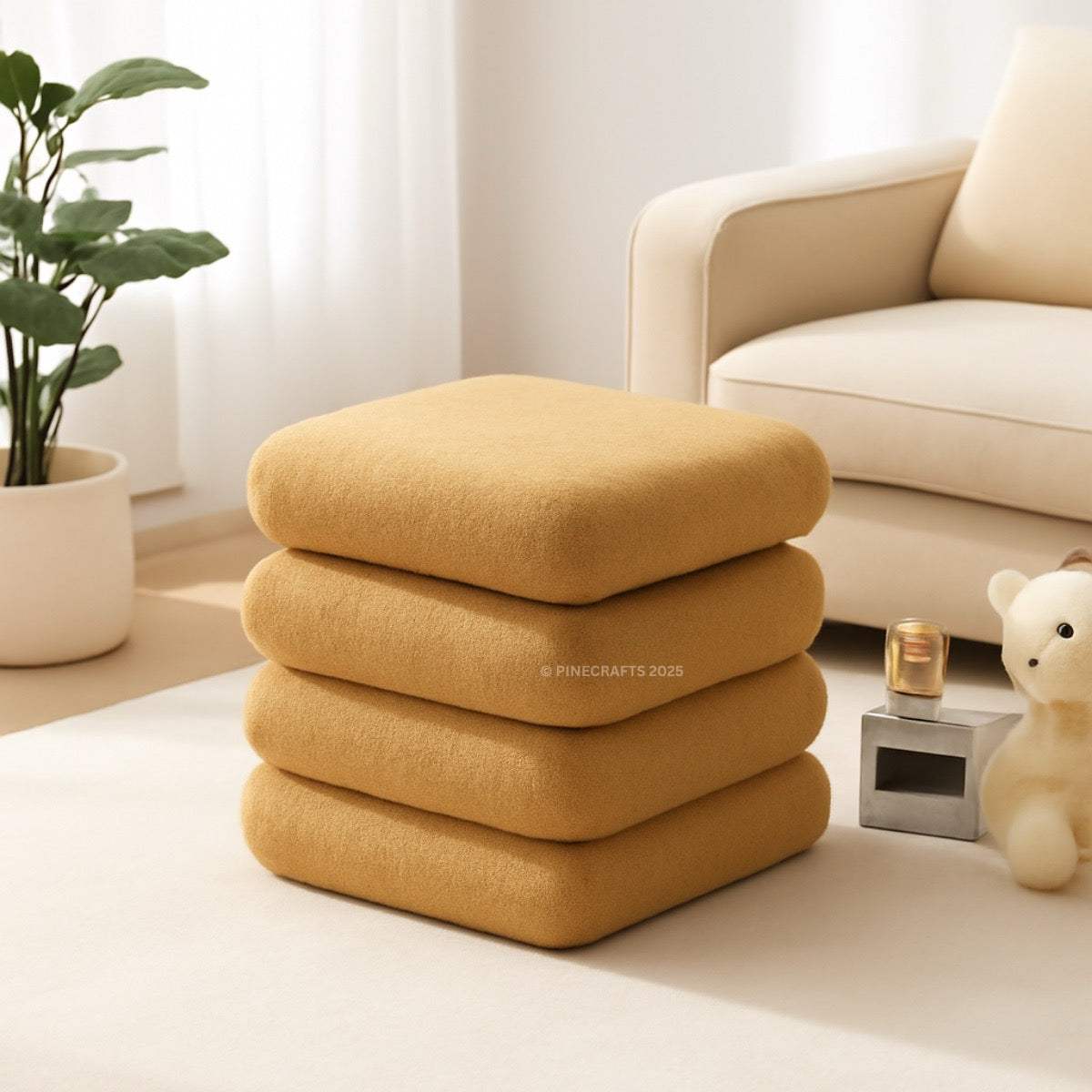 Stack of mustard yellow cushions on a light-colored floor with a beige sofa and plant in the background.