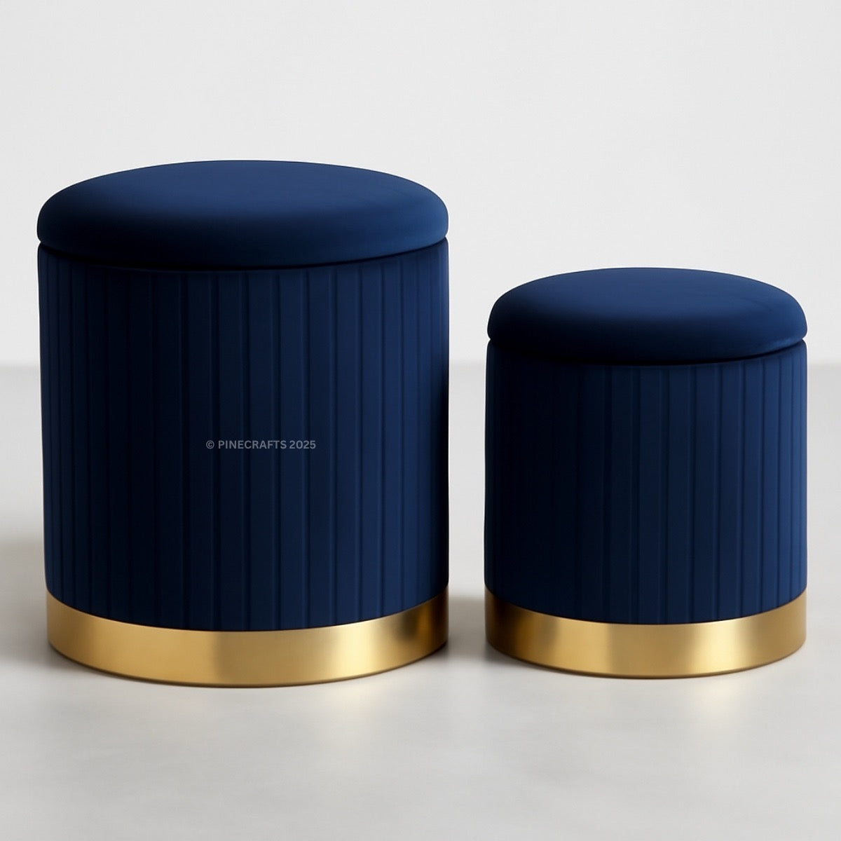 Two navy blue ottomans with gold bases on a light gray background