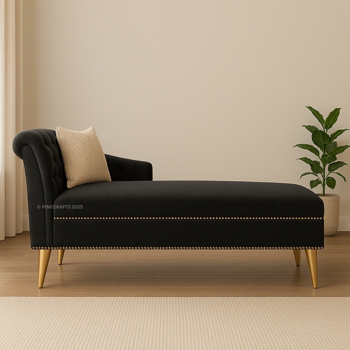 Black chaise lounge with gold legs and a beige pillow in a room with a plant and neutral walls.