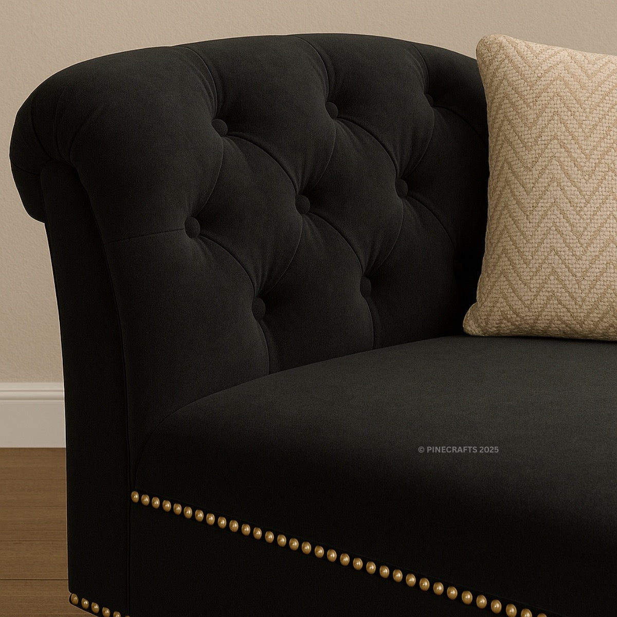 Black tufted sofa with a beige pillow against a beige wall.