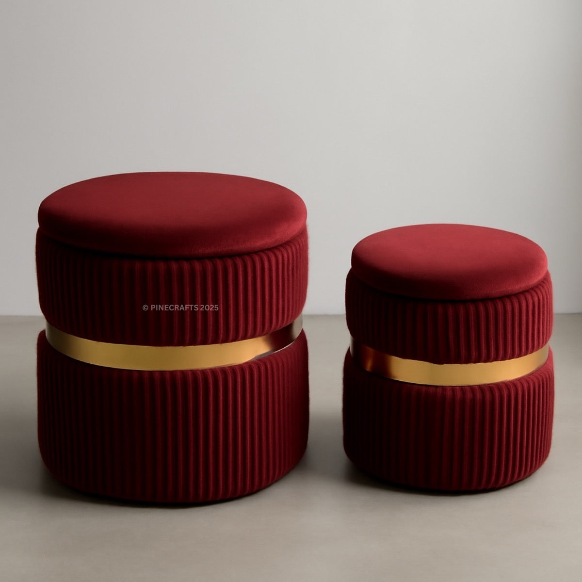 Two red cylindrical stools with gold bands on a neutral background