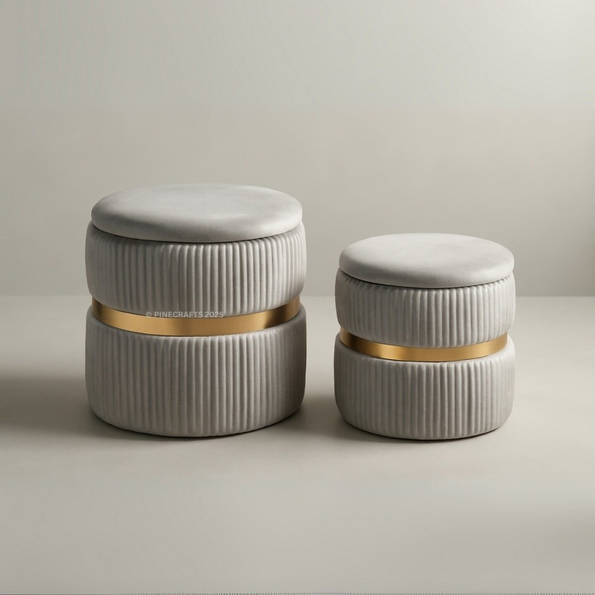 Two cylindrical ottomans with ribbed texture and gold bands on a neutral background