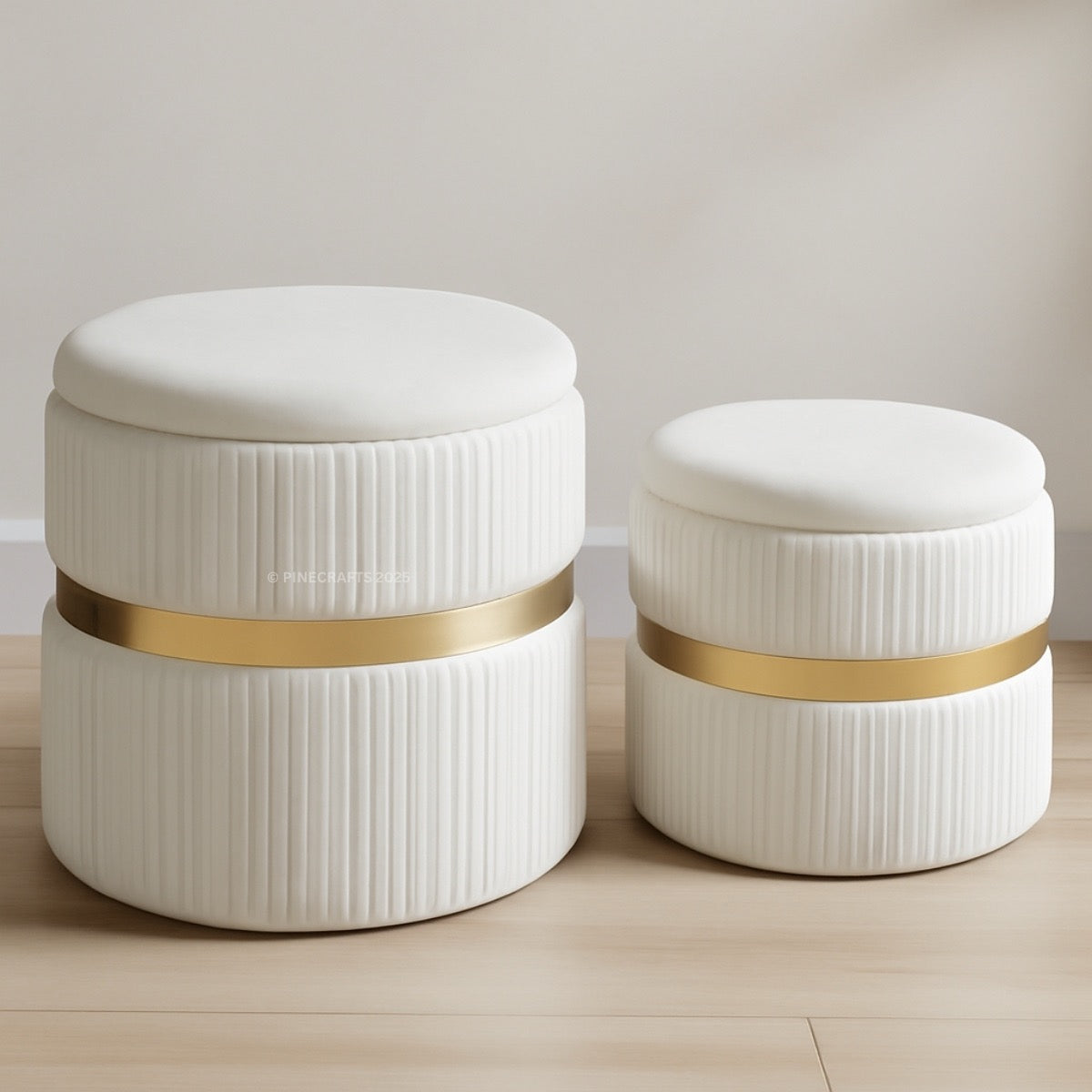 Two white ottomans with gold bands on a wooden floor.