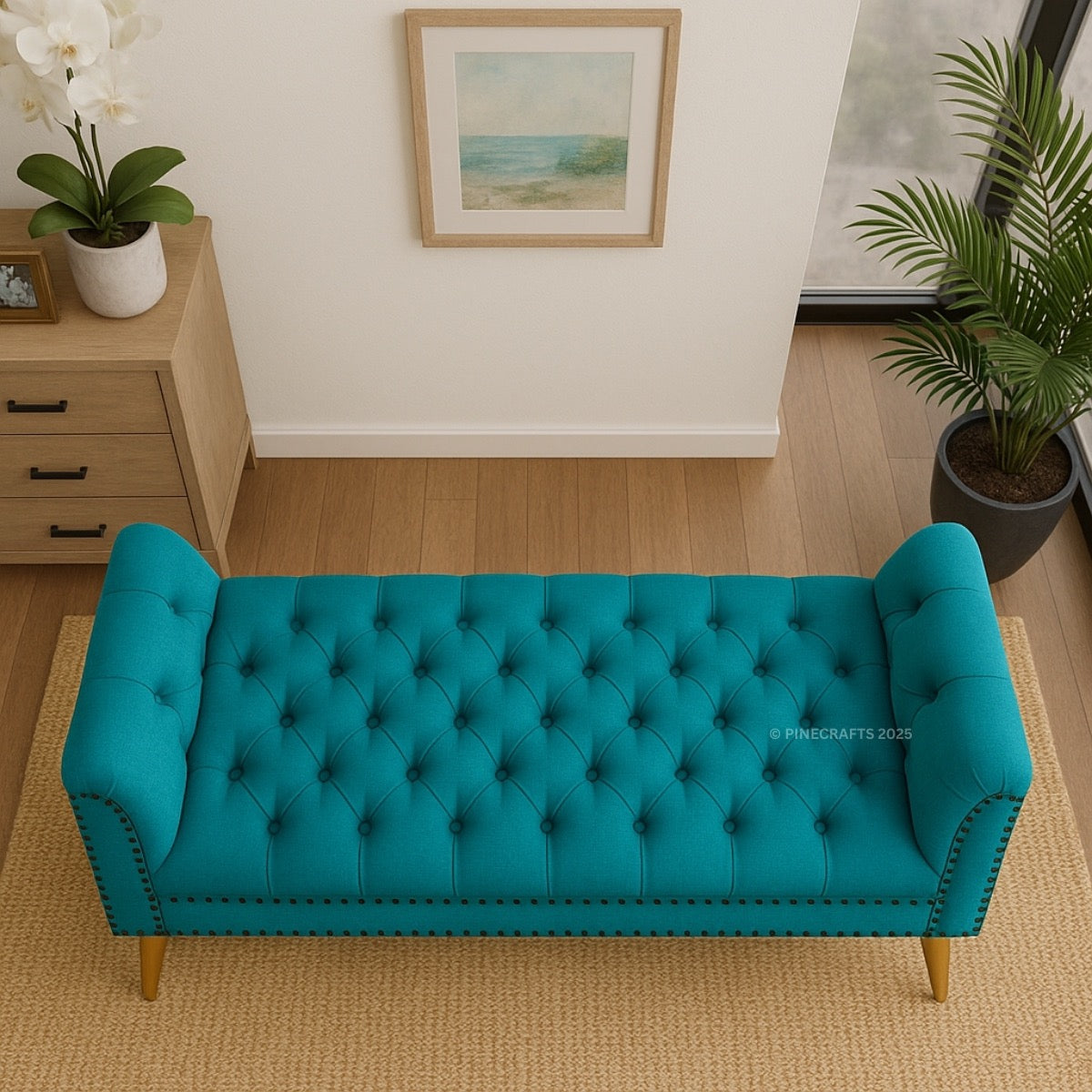 Teal tufted bench in a room with plants and a painting on the wall.