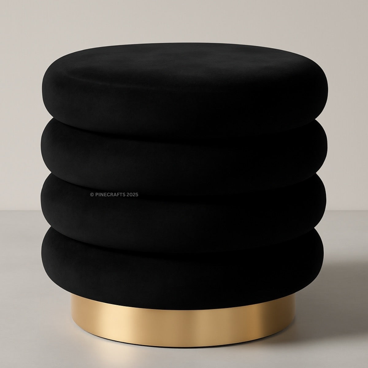 Black cushioned stool with a gold base on a neutral background