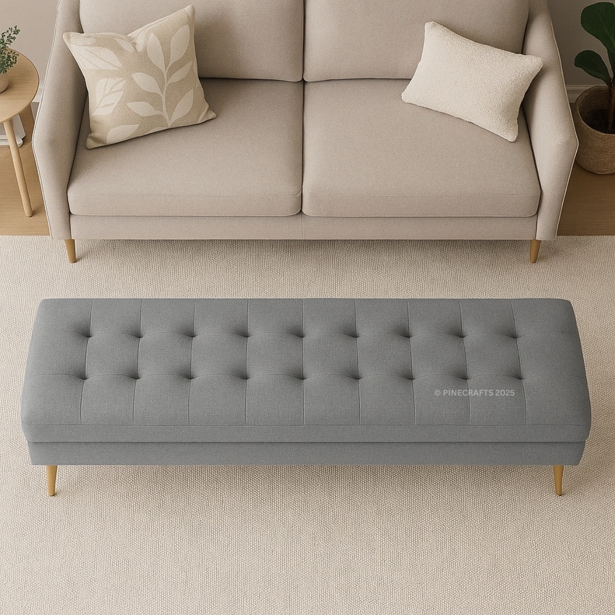 Gray tufted bench in front of a beige sofa with decorative pillows.
