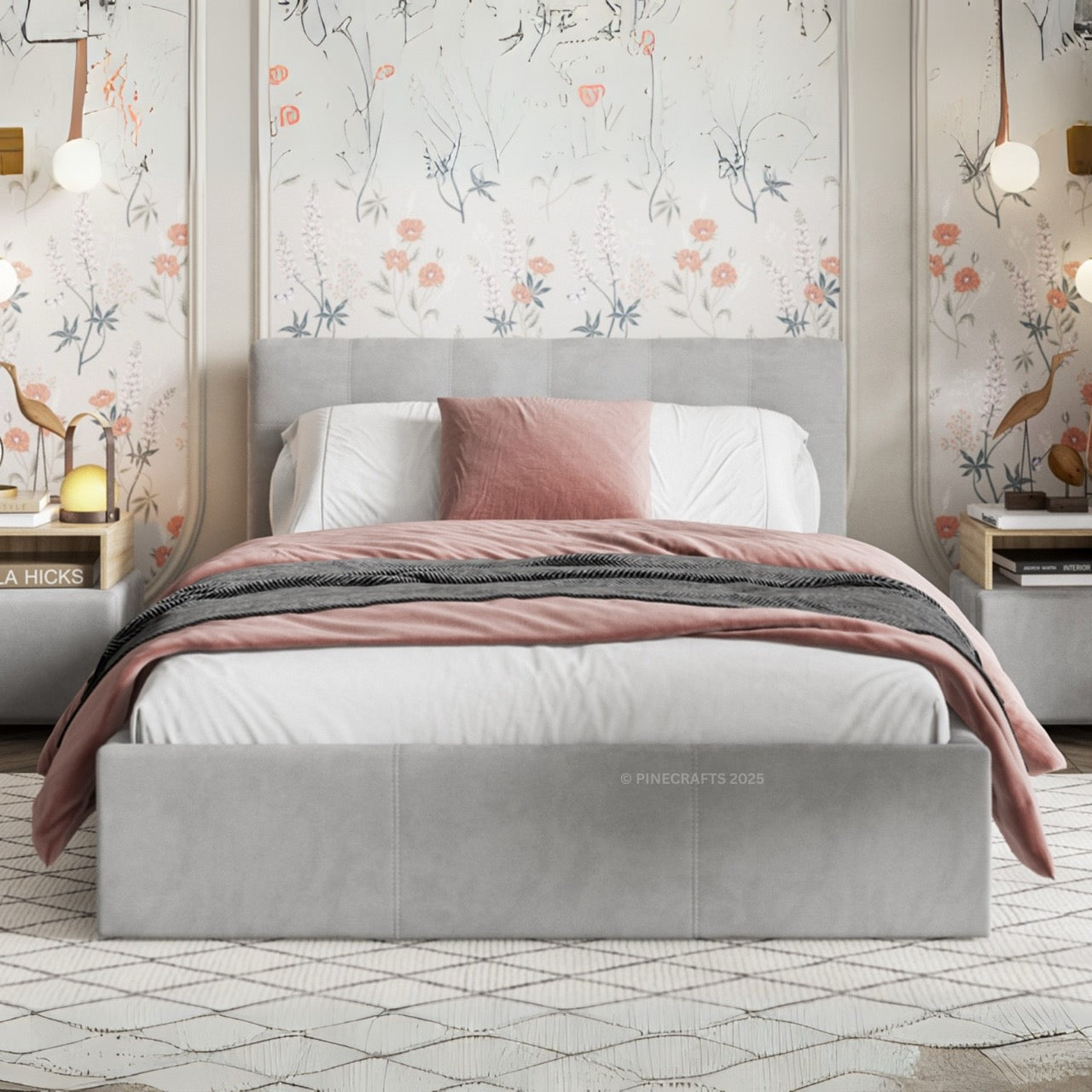 Gray upholstered bed with pink bedding in a room with floral wallpaper.