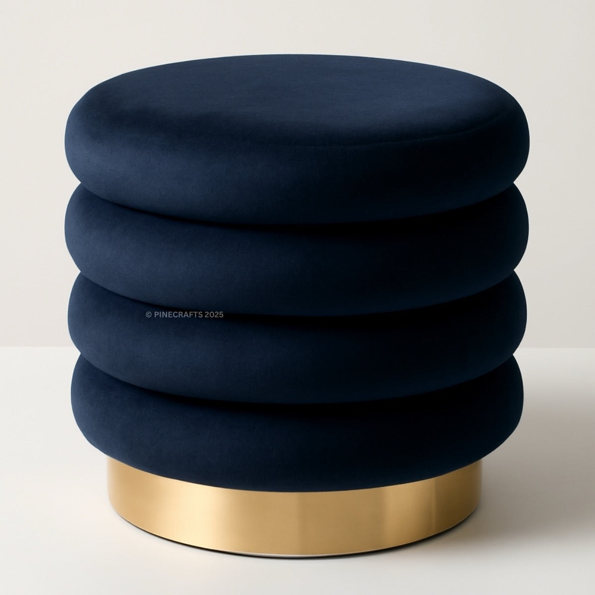 Navy blue ottoman with a gold base on a light gray background