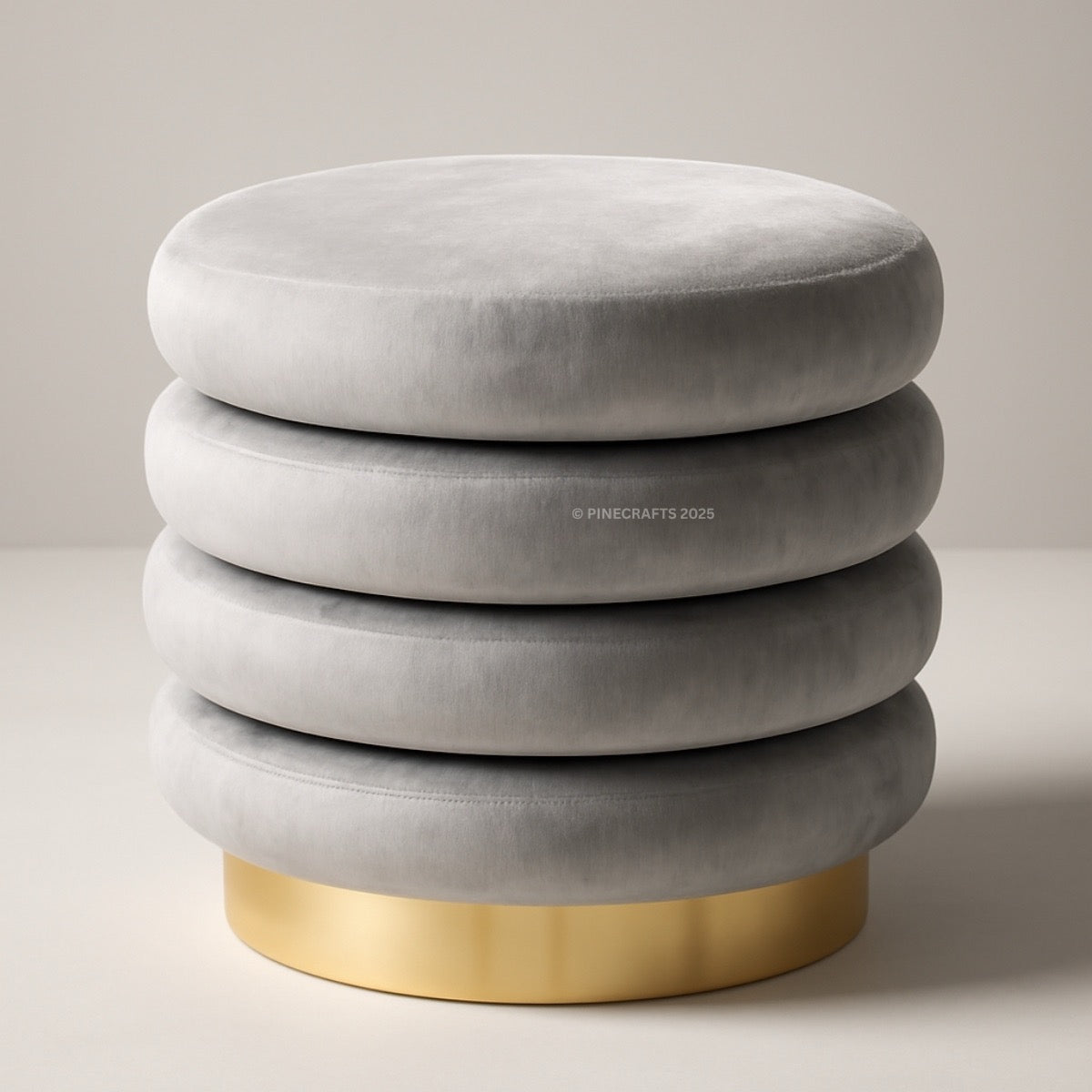 Gray velvet ottoman with a gold base on a neutral background