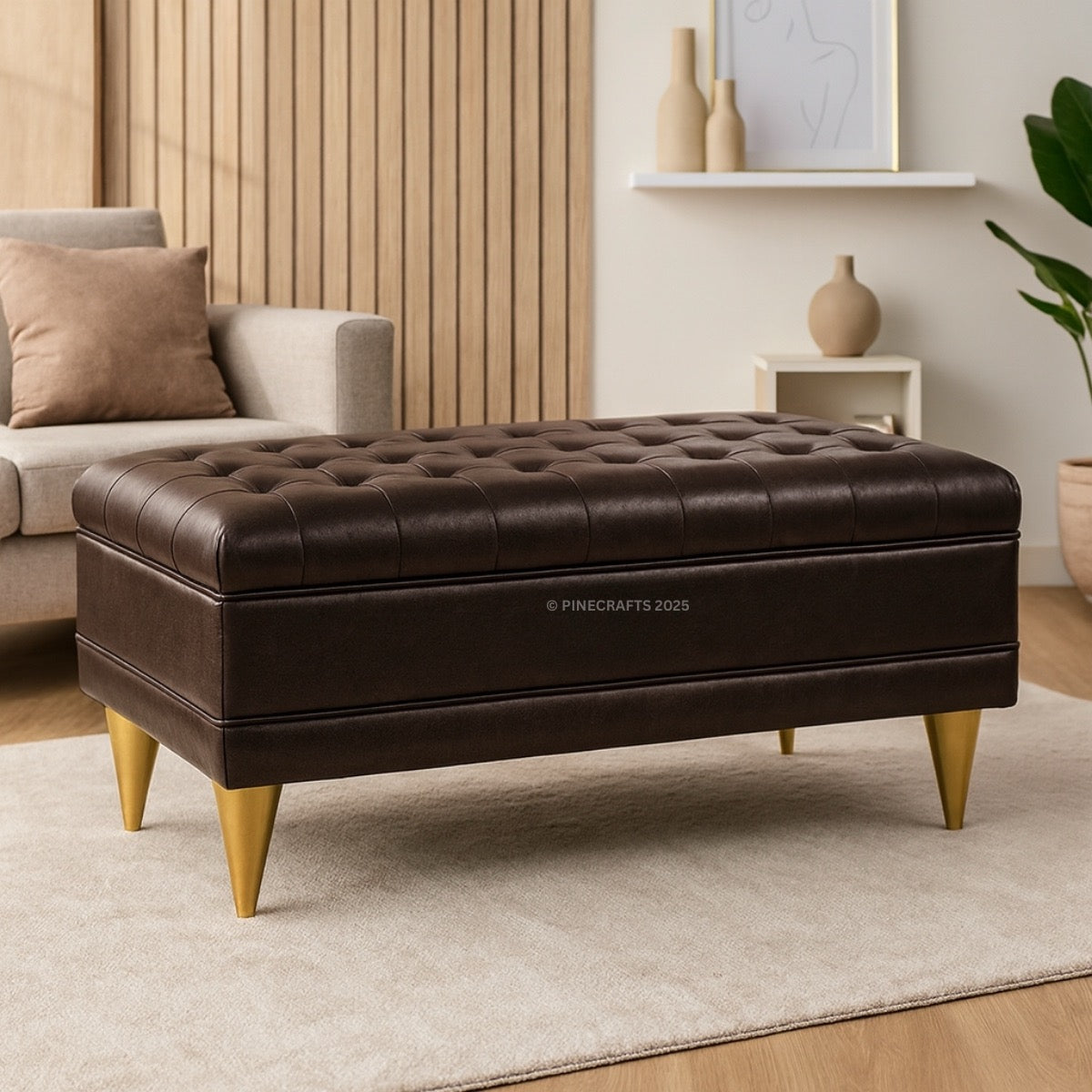 Brown tufted ottoman with gold legs in a living room setting.