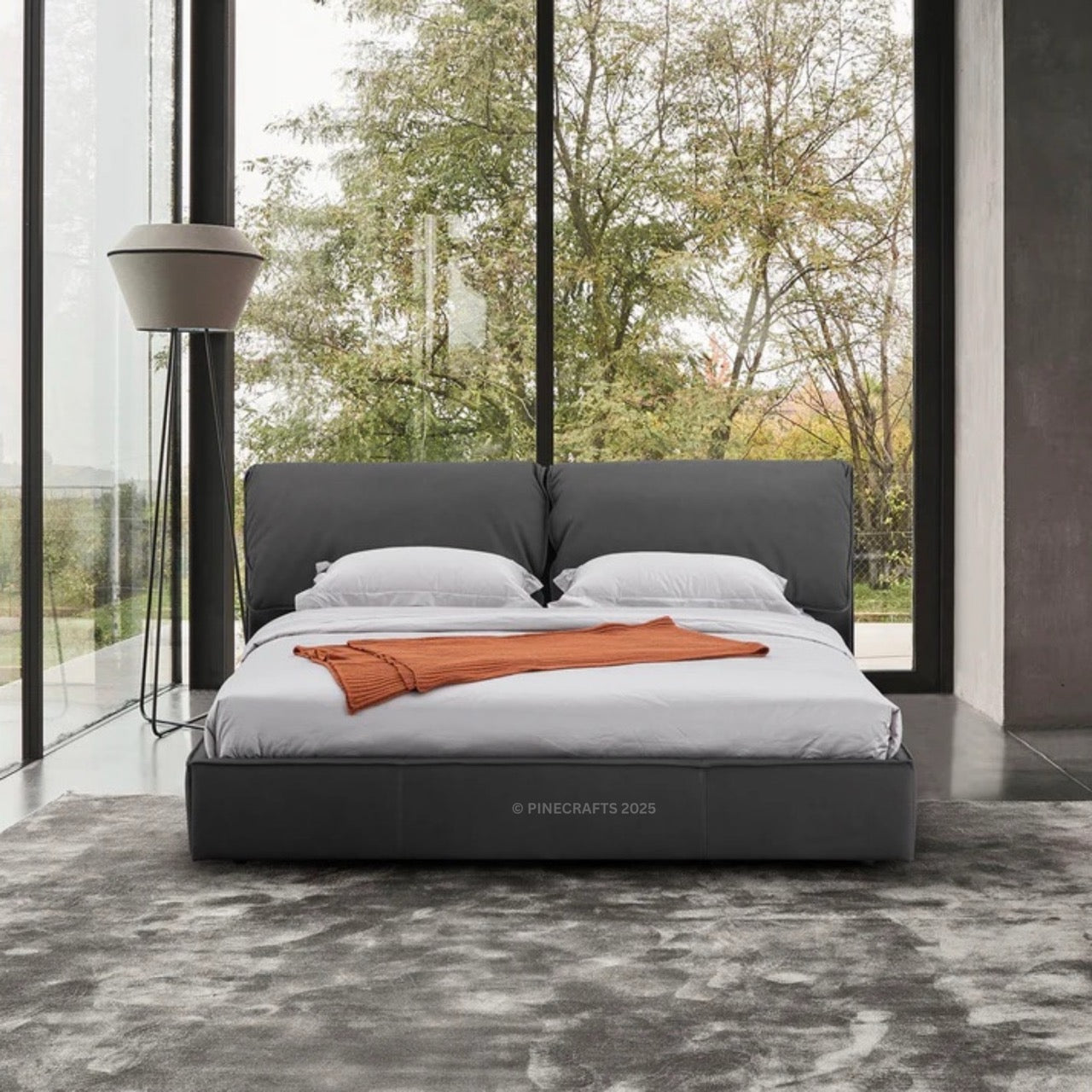 Modern bed with gray headboard and white bedding in a room with large windows.