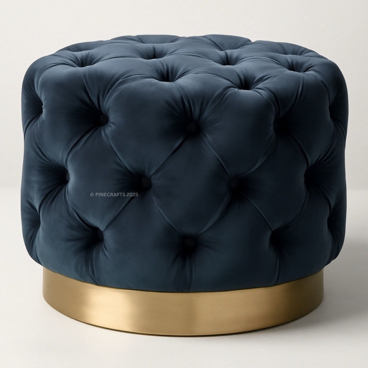 Blue tufted ottoman with a gold base on a light background