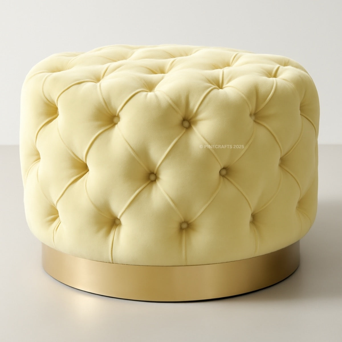 Round tufted ottoman with a gold base on a light gray background