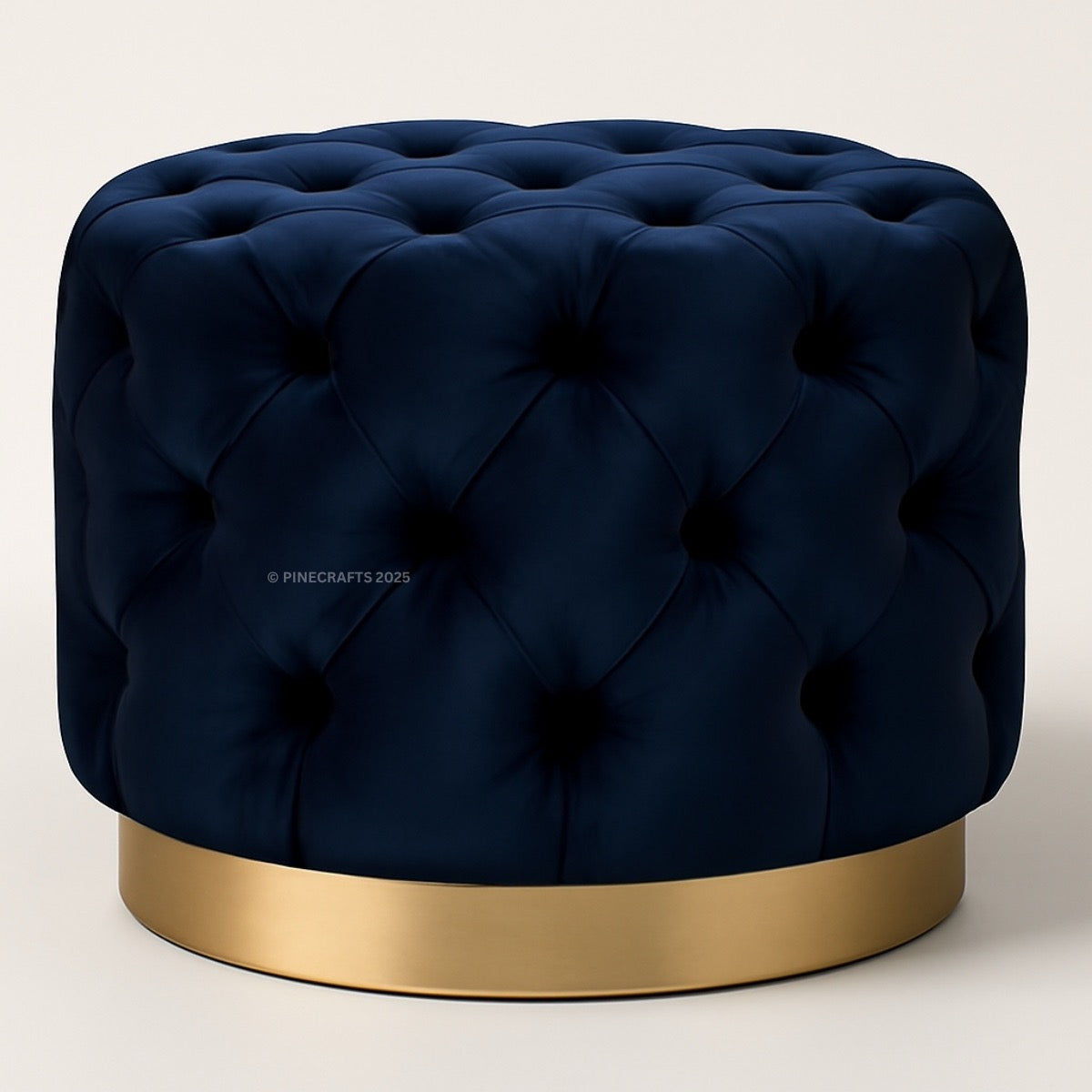 Navy blue tufted ottoman with a gold base on a light beige background
