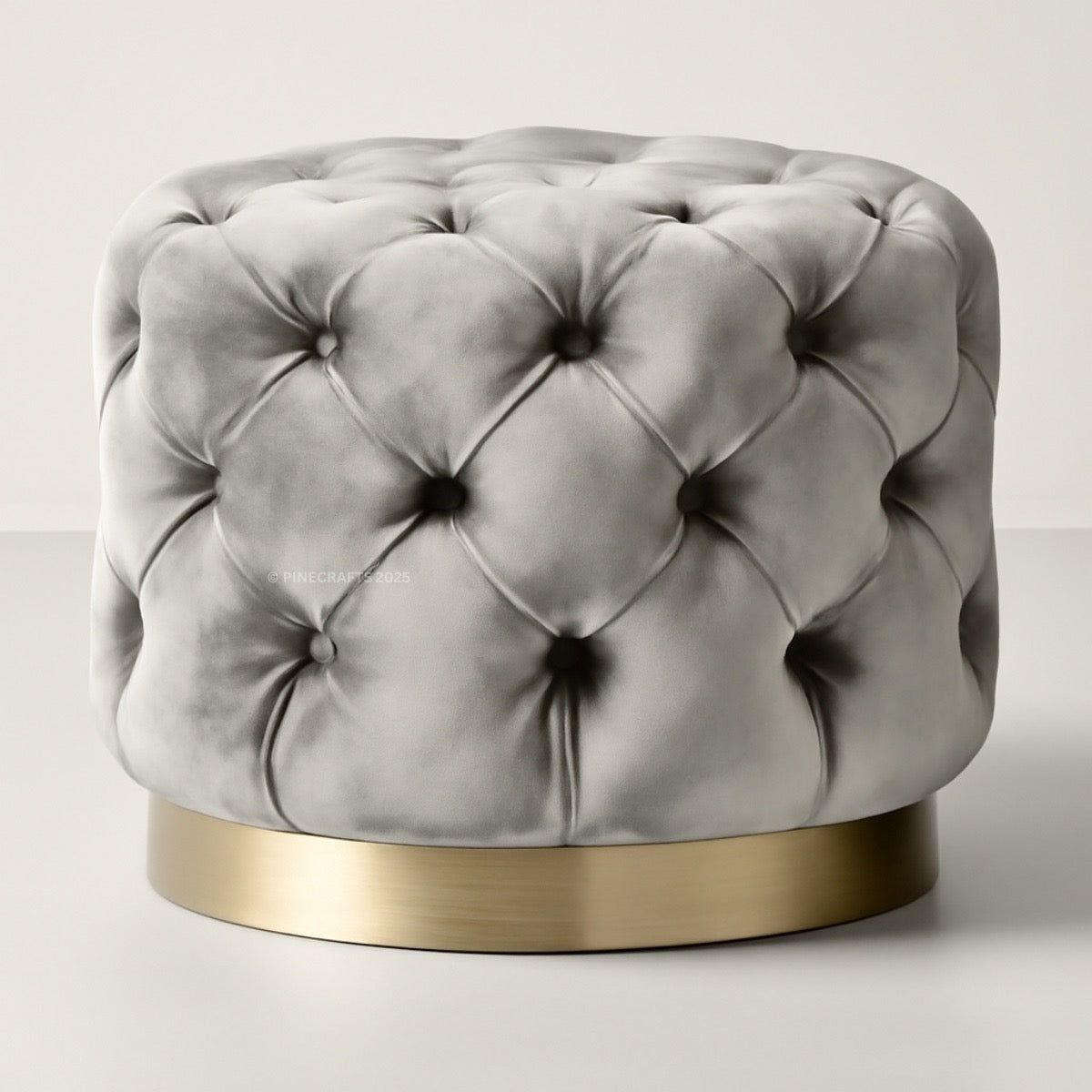 Gray tufted ottoman with a gold base on a light gray background