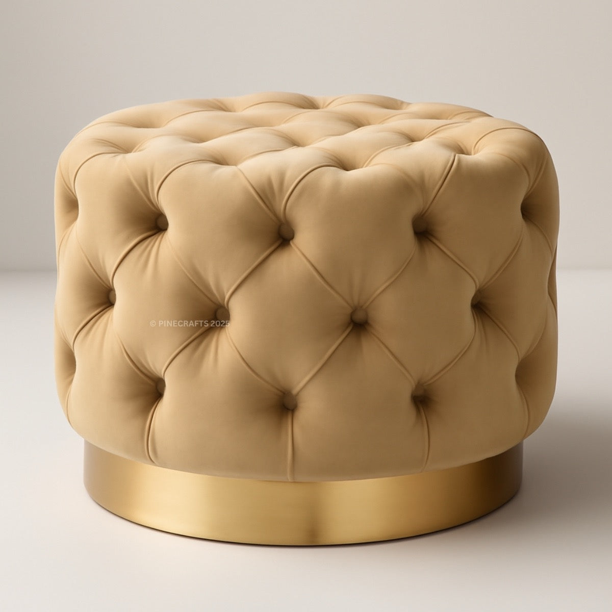 Beige tufted ottoman with a gold base on a light gray background