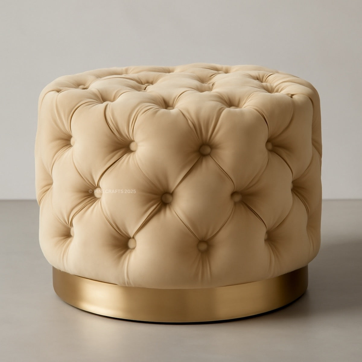 Beige tufted ottoman with a gold base on a neutral background